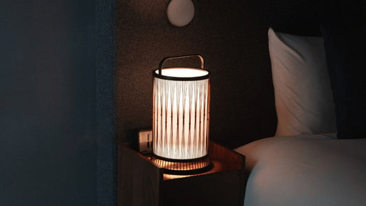 Traditional Japanese bamboo floor lamp "Moonlight", crafted with 800-year-old Shizuoka techniques, resting on a bedside table.