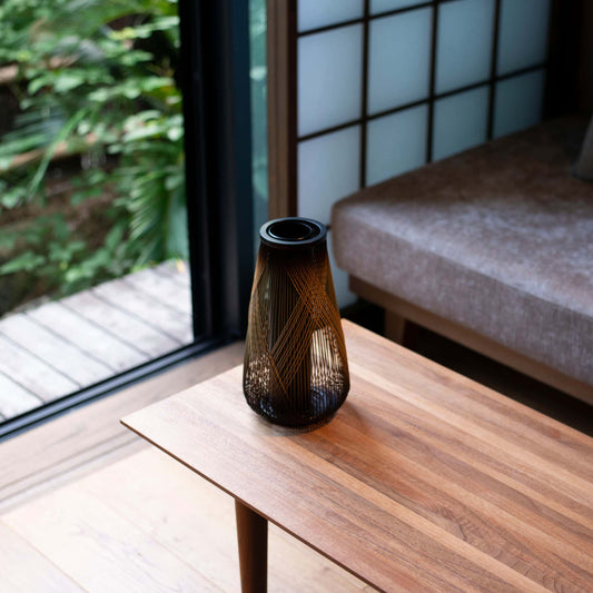 A Japanese bamboo Ikebana vase on a wooden table in Japandi living room.