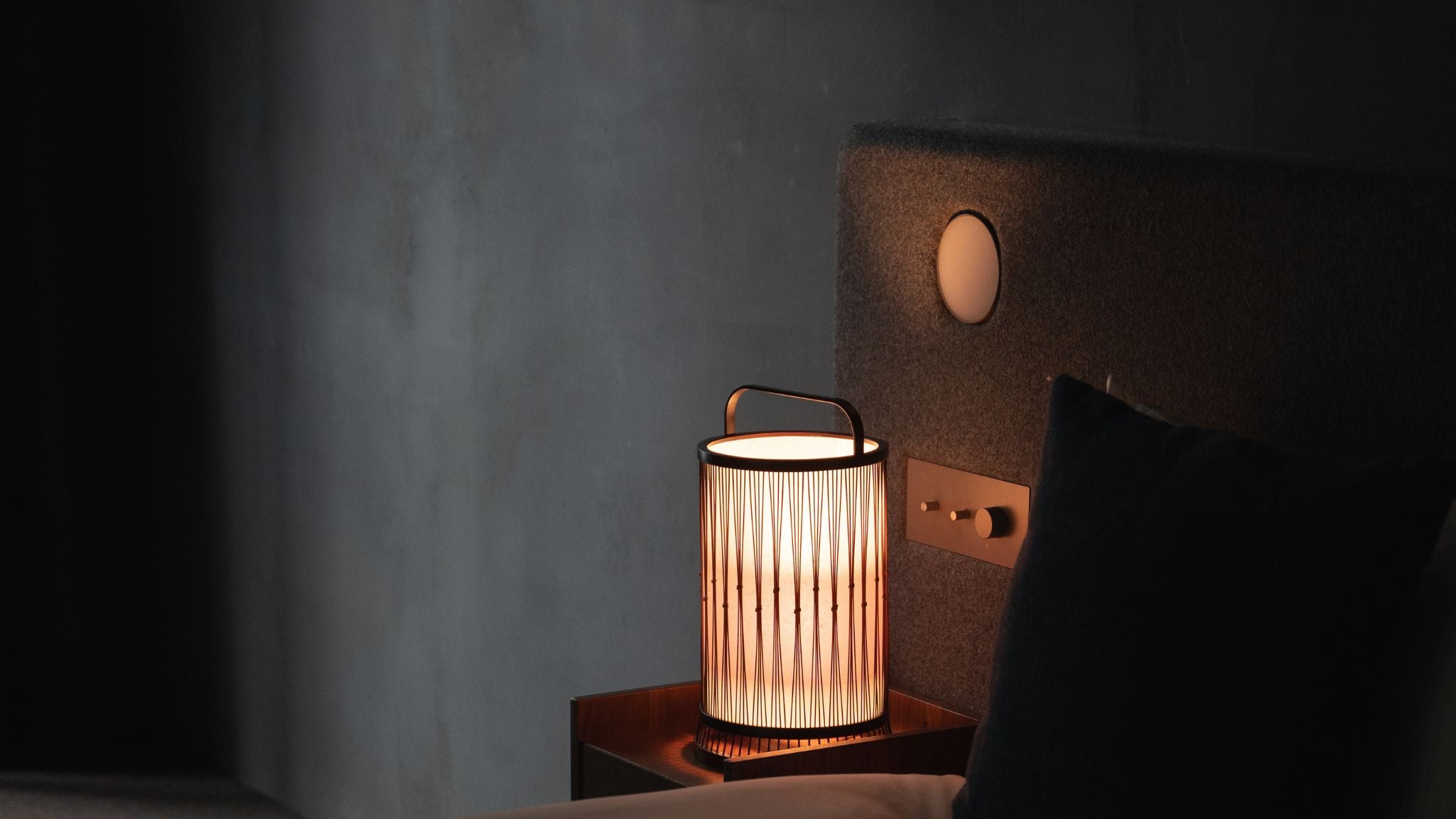 Traditional Japanese bamboo floor lamp crafted with ancient techniques, casting a soft glow on a bedside table in a Japandi-style bedroom.