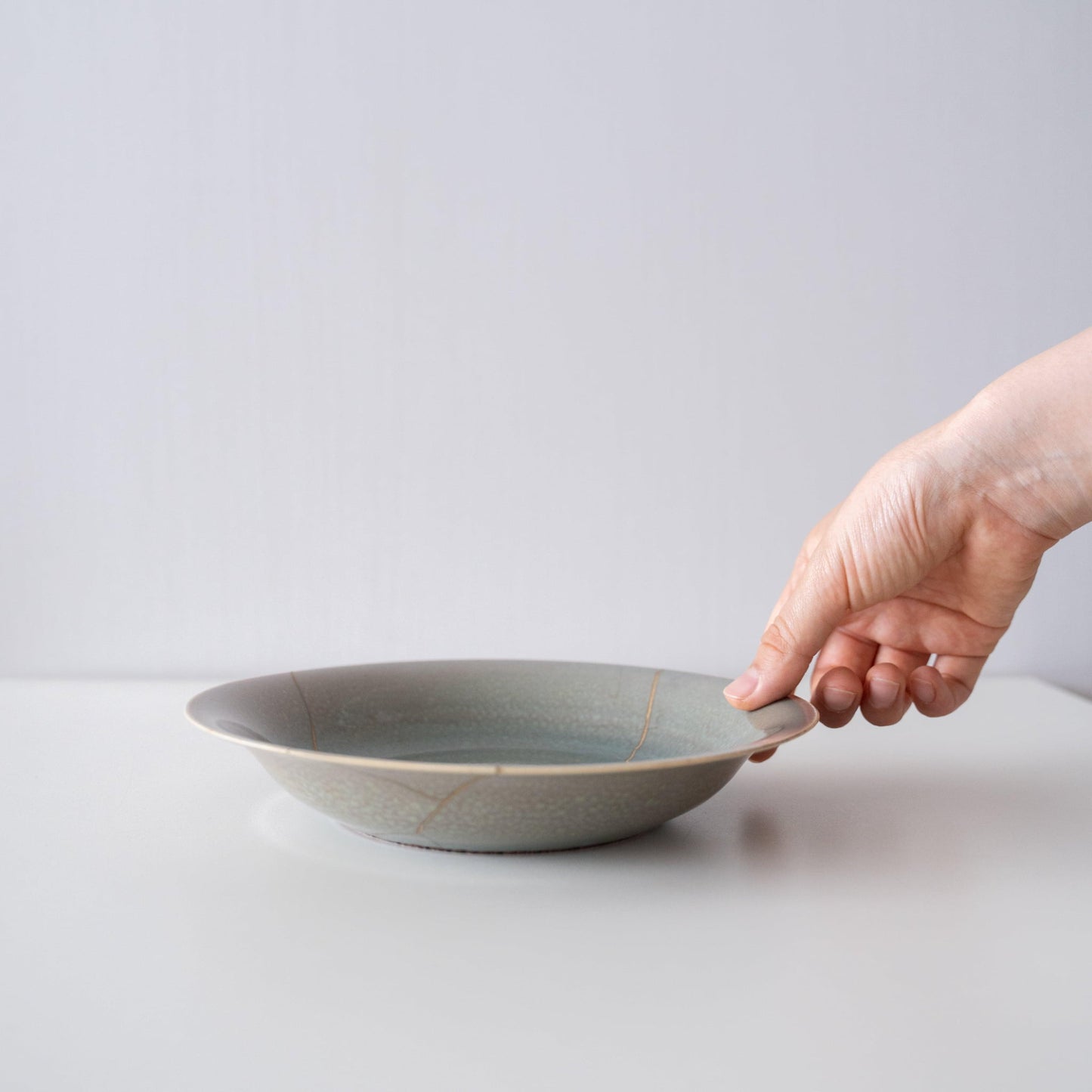 Hand holding Kintsugi Bowl "Four Color Yohenyu", showing its size and how it fits in the hand