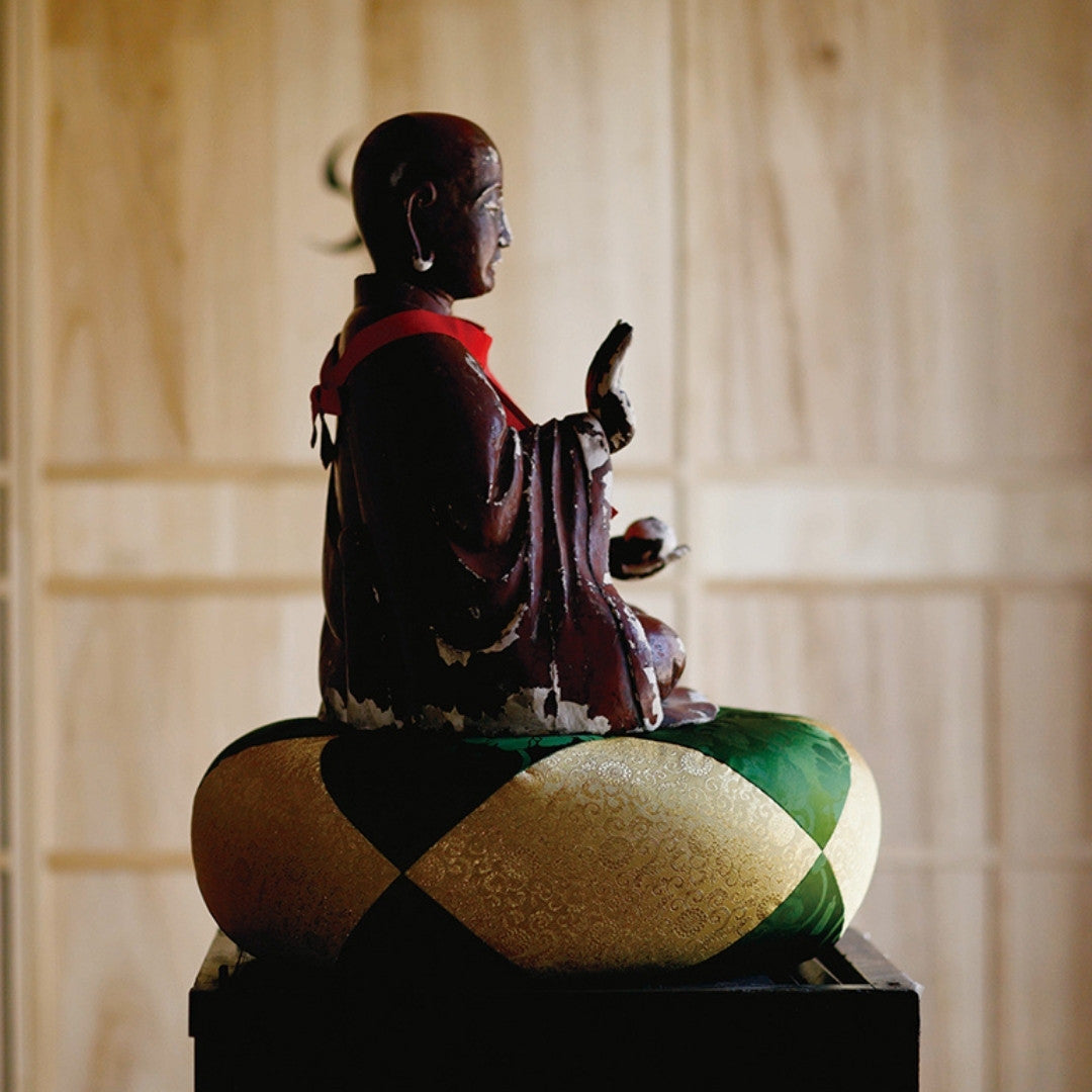 Buddha statue seated on Sakae Kinran kinran meditation cushion, traditional temple design