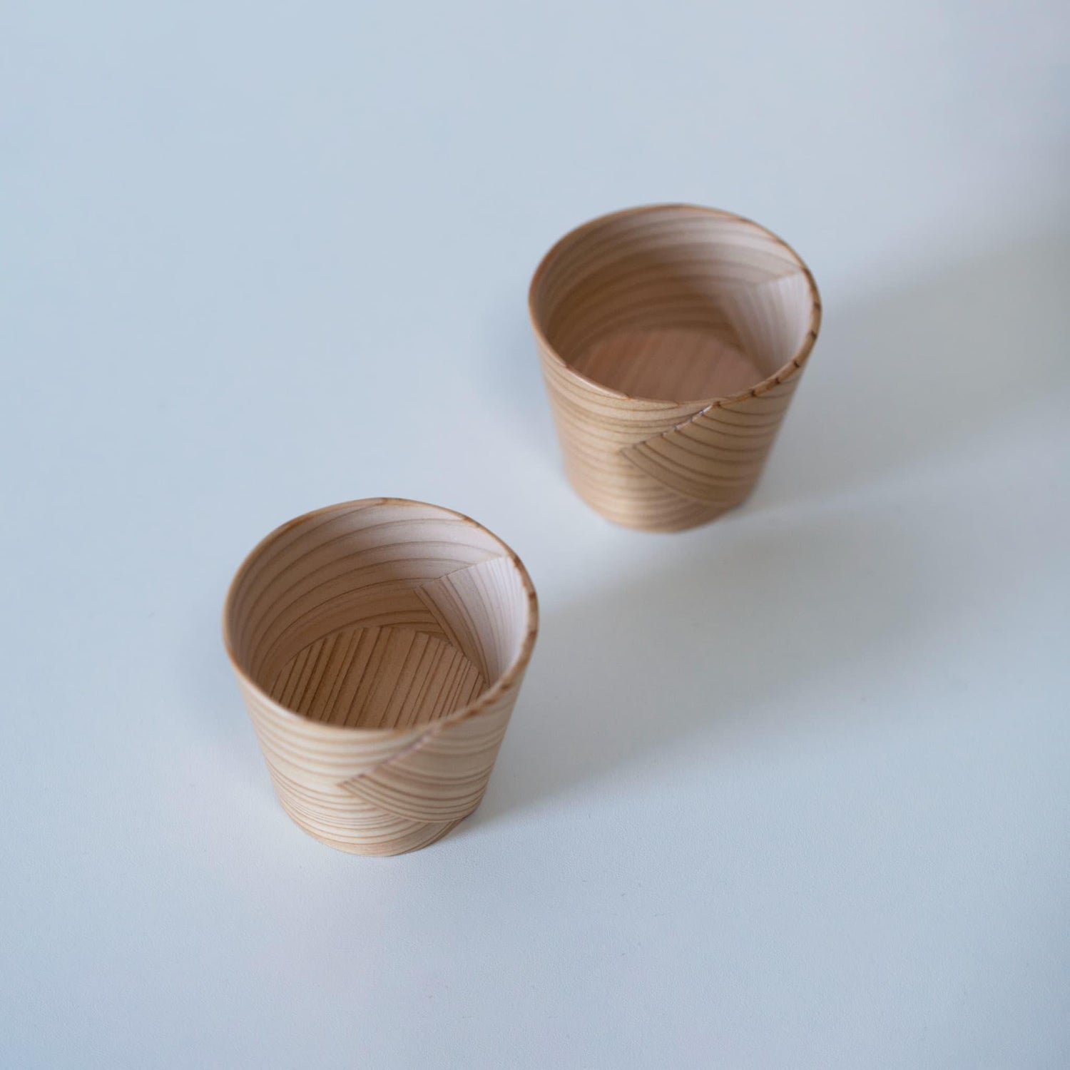 Two sake cups made of Akita cedar by a 76-year-old craftsman using traditional Magewappa bending techniques.