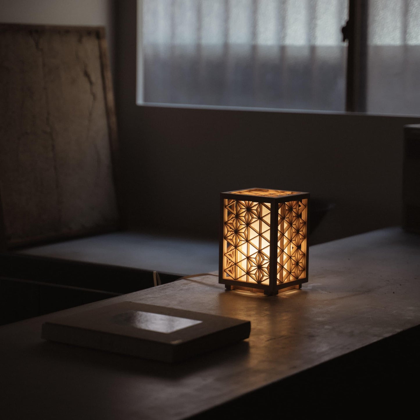 Japanese kumiko lamp, meticulously handcrafted with 360 pieces of premium Akita cedar, illuminating a minimalist Japandi-style living room with its warm, geometric glow.