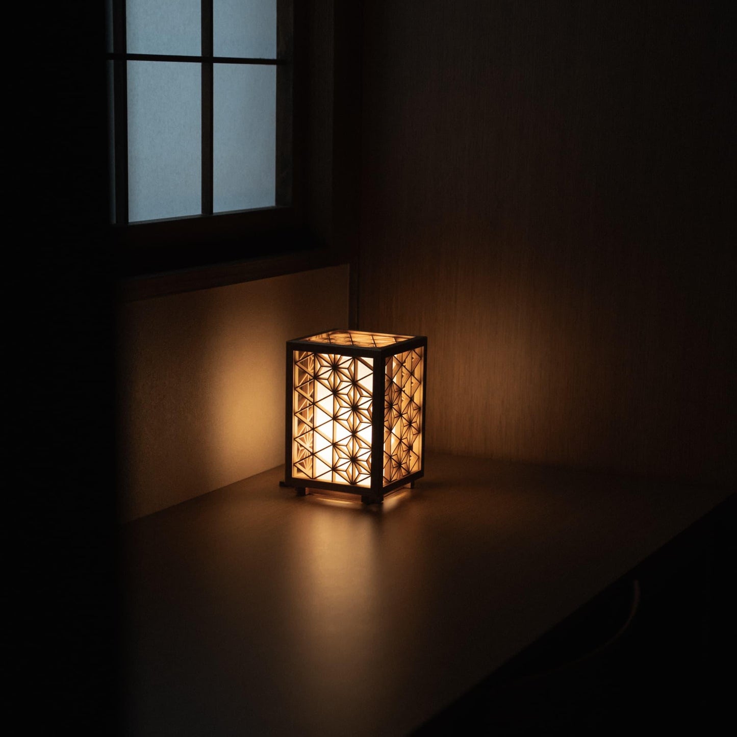 Kumiko table lamp, meticulously handcrafted with 600 pieces of premium Akita cedar, casting a warm and inviting glow on a bedside table in a traditional Japanese bedroom.