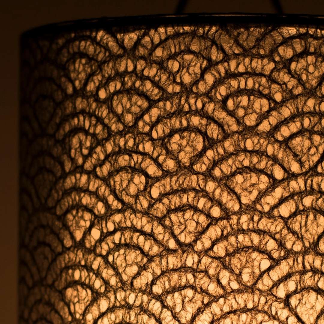 Intricate black lace detail illuminated in Japanese paper table lamp 'Lace Washi Black' - stylish paper table lamp for bedroom ambiance