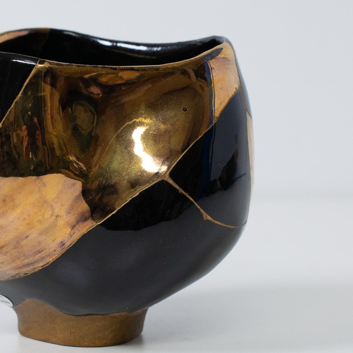 Close-up of kintsugi matcha bowl emphasizing gold lacquer and reflective texture