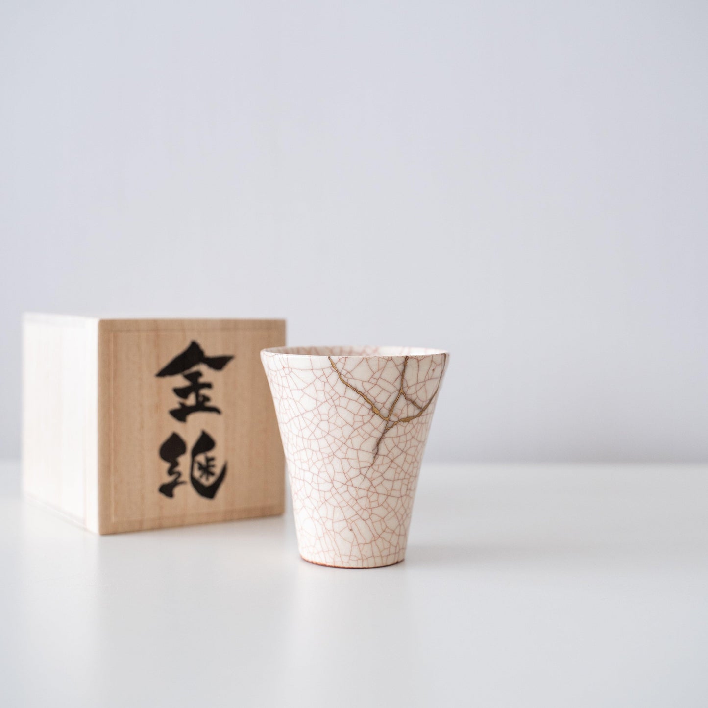 Kintsugi repaired white cup and paulownia wood box gift set, symbolizing the Japanese aesthetic of finding beauty in imperfection.