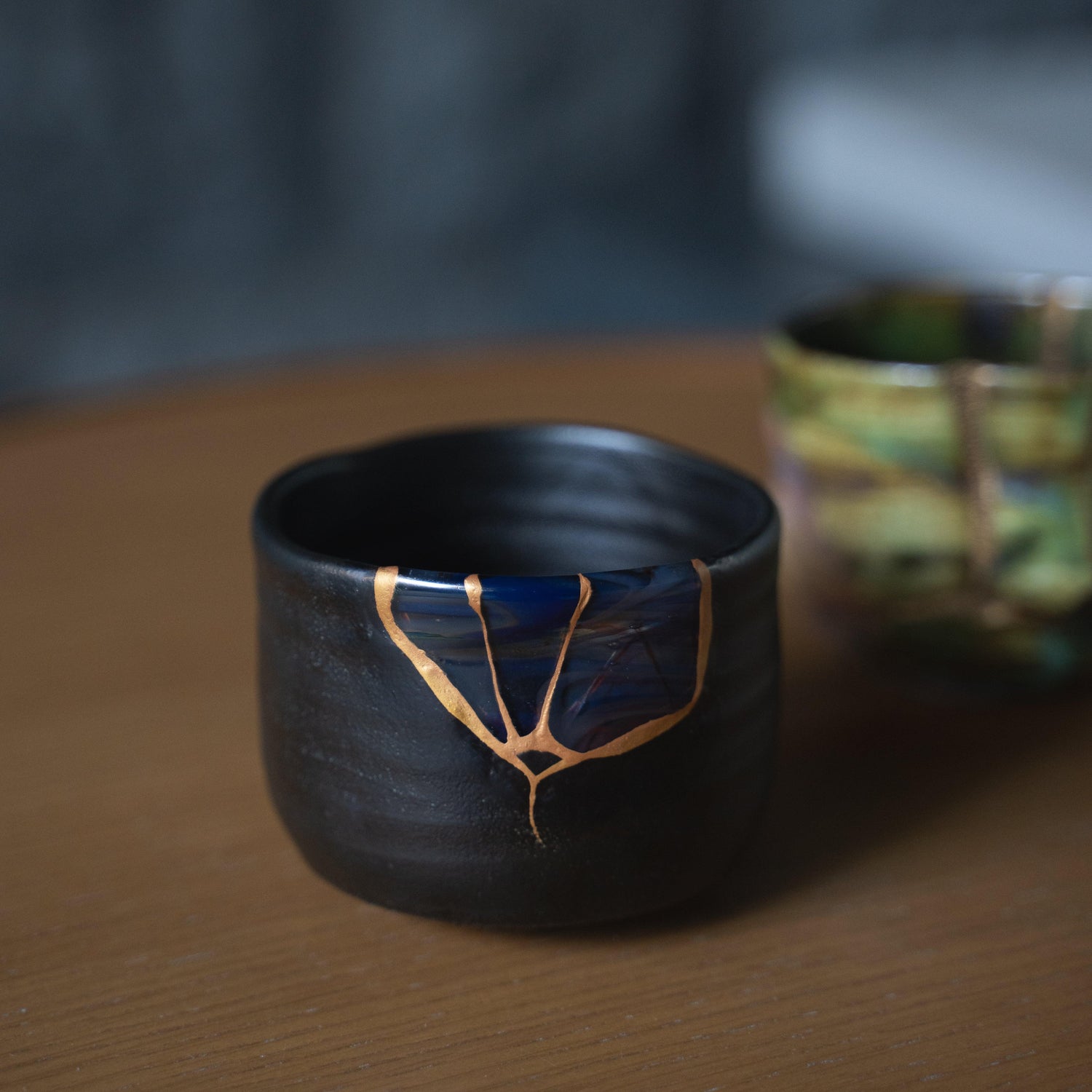 Jet-black Japanese tea bowl, adorned with the exquisite golden repairs of kintsugi,