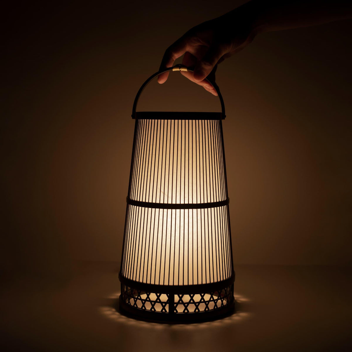 "Hand die een traditionele Japanse bamboelamp vasthoudt, handgemaakt in Shizuoka met 800 jaar oude technieken."