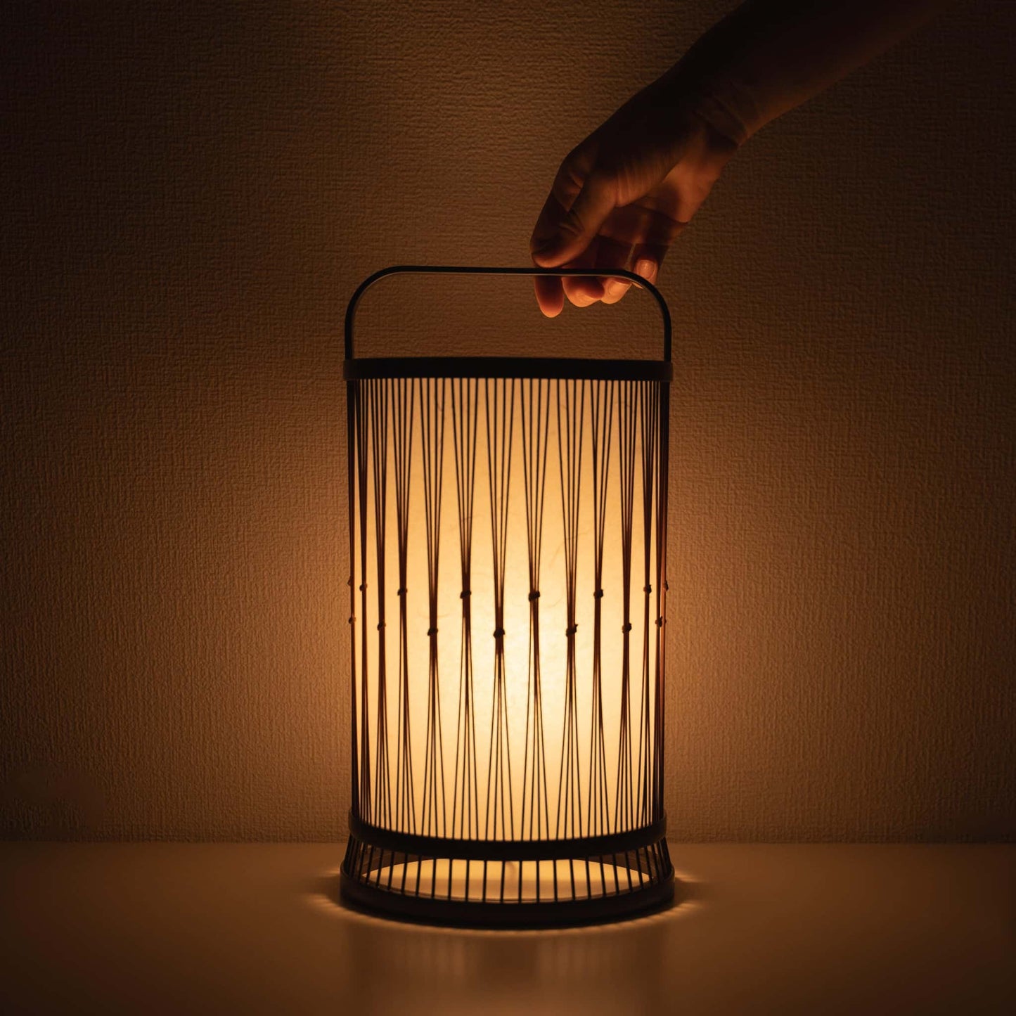 Hand holding a traditional Japanese bamboo lamp, handcrafted in Shizuoka with 800-year-old techniques.