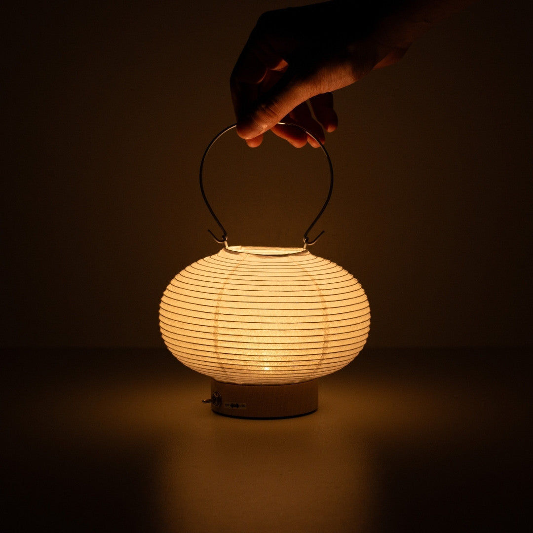 Hand holding Japanese paper table lamp RIN 03, portable rounded Japanese paper lamp