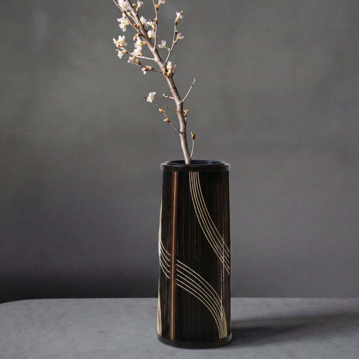 Japansk bambusvase med titlen "Flowing Water" udstillet på et gråt hotelbord.