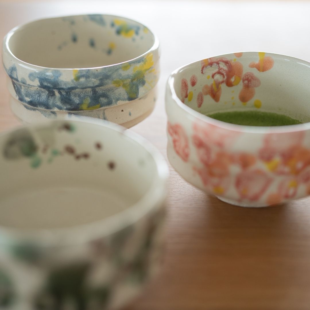 Collection of Japanese matcha bowls (Flower, Splash, Forest) for the tea ceremony, emphasizing the vibrant green matcha contrasting with the pink and white glaze.