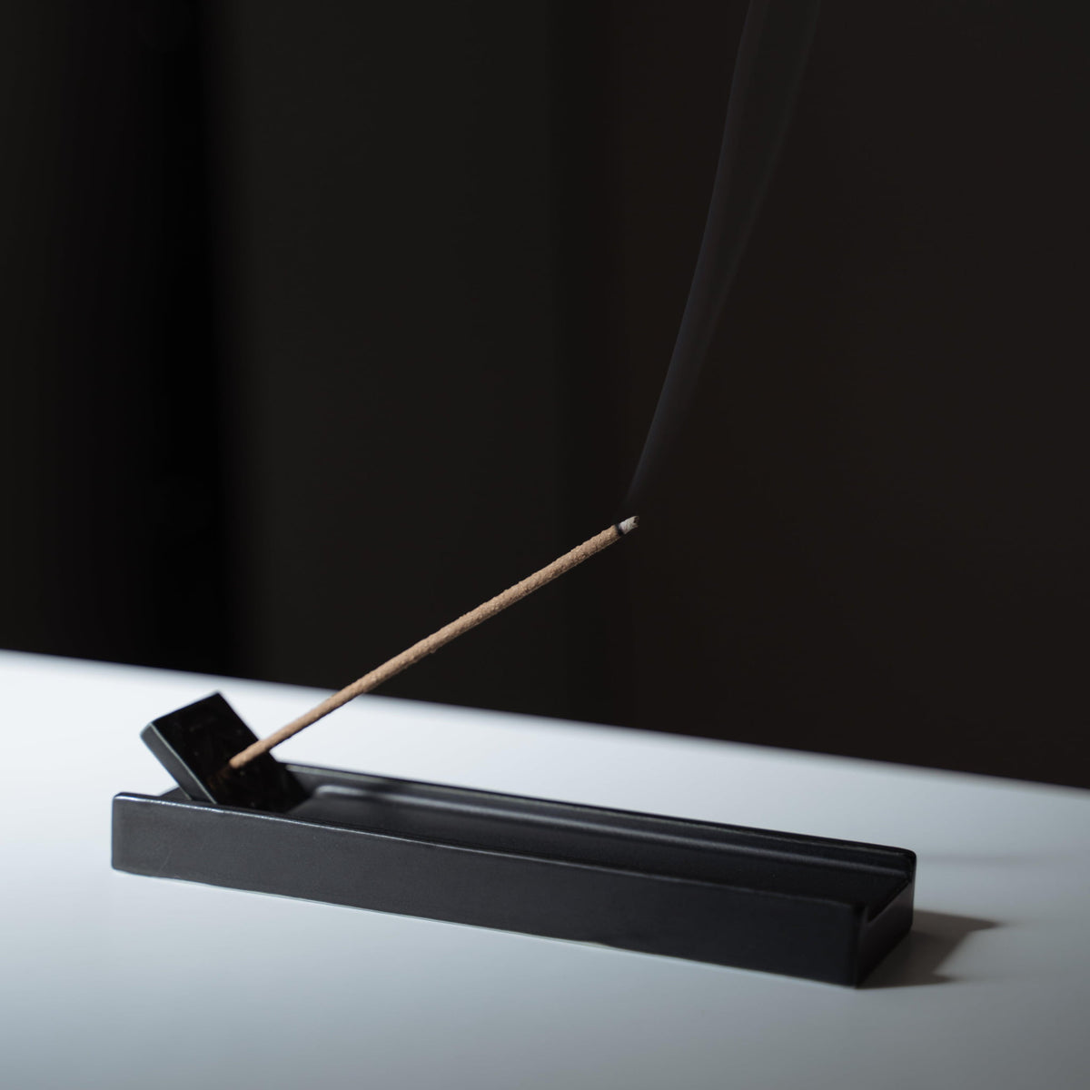 Un bâtonnet d'encens en bois de Hinoki sur une coupelle à encens en porcelaine d'Arita.