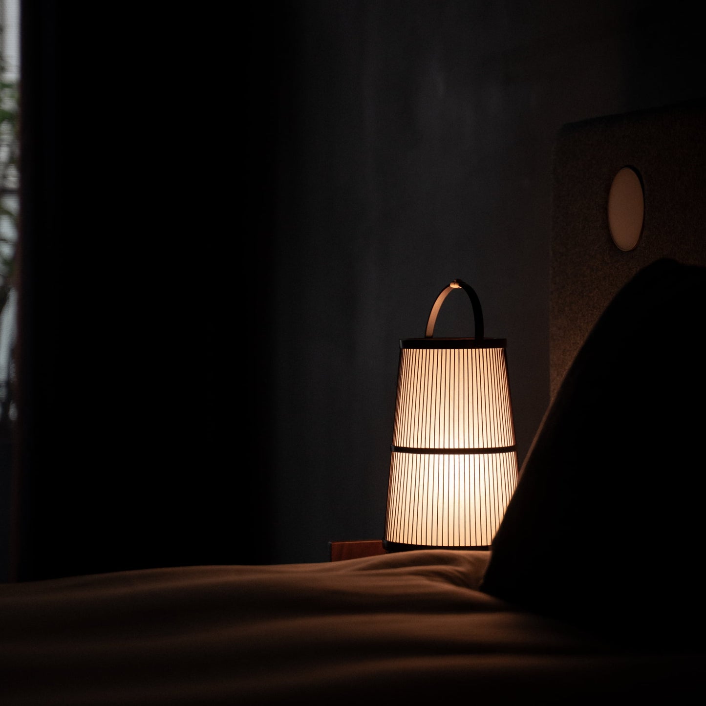 A Japanese bamboo lamp placed on a bedside table in a Japandi-style bedroom.
