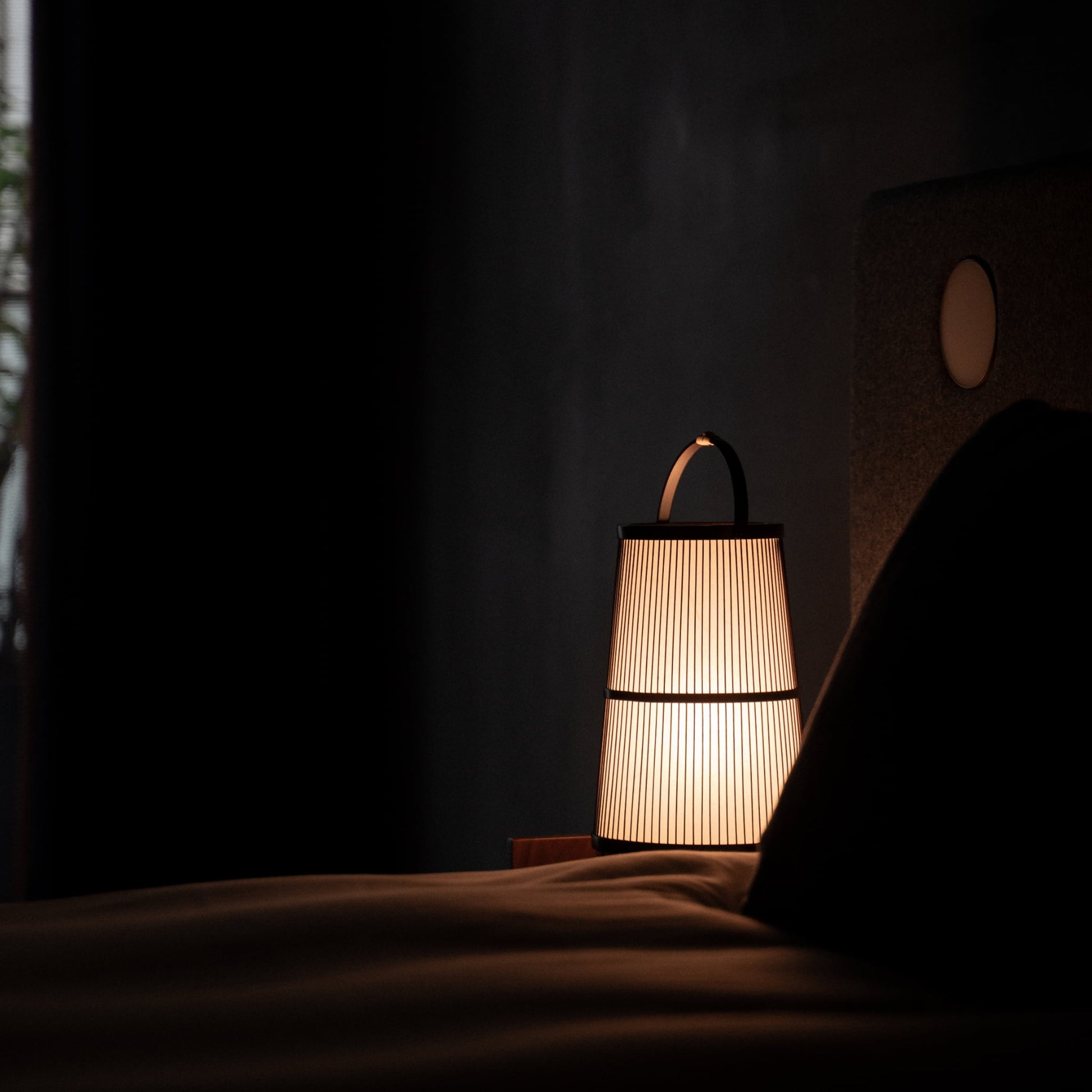 A Japanese bamboo lamp placed on a bedside table in a Japandi-style bedroom.