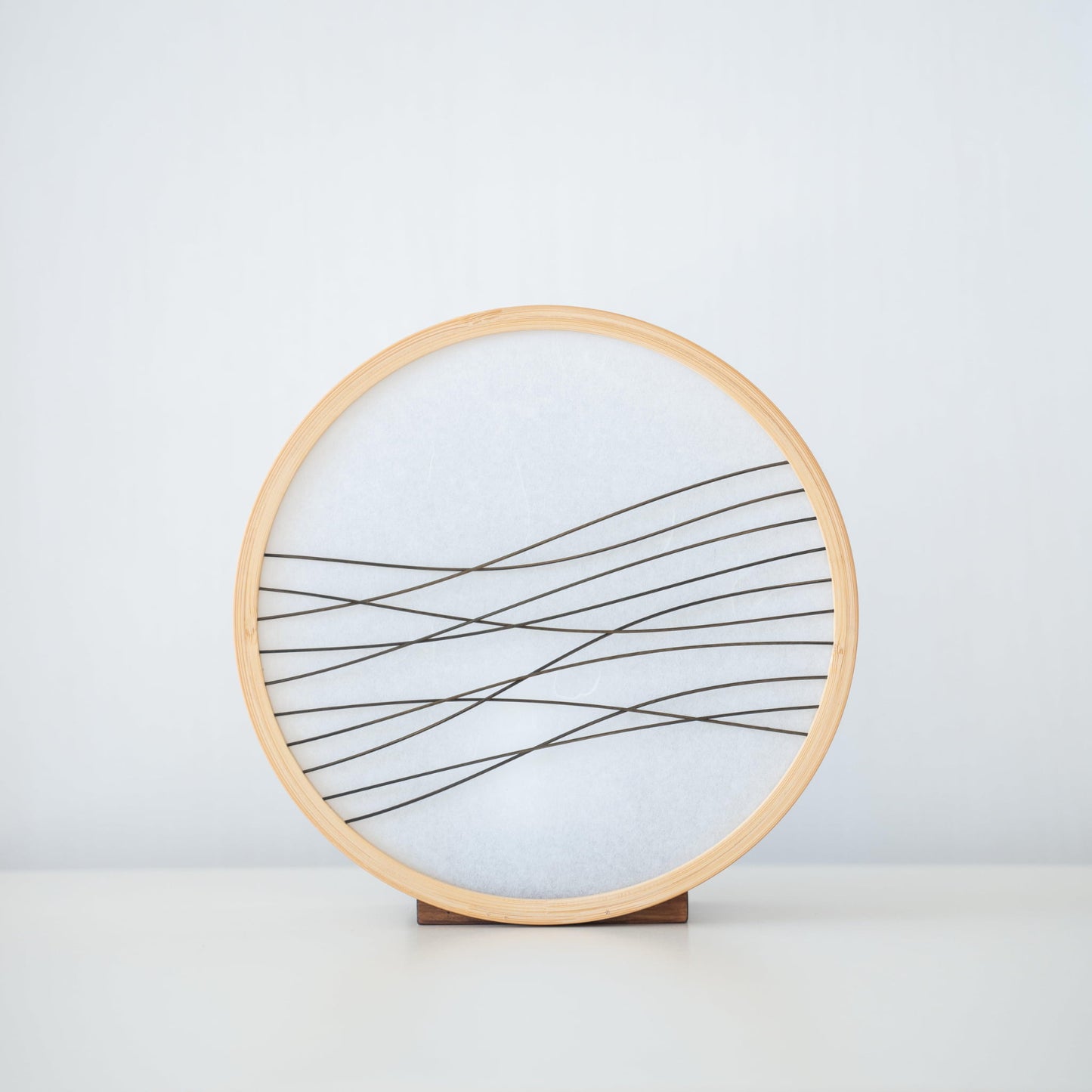 Traditional Japanese bamboo lamp handcrafted in Shizuoka with 800-year-old techniques. Circular wooden frame with washi paper shade featuring delicate bamboo accents. Simple yet elegant design casts a soft, warm glow.