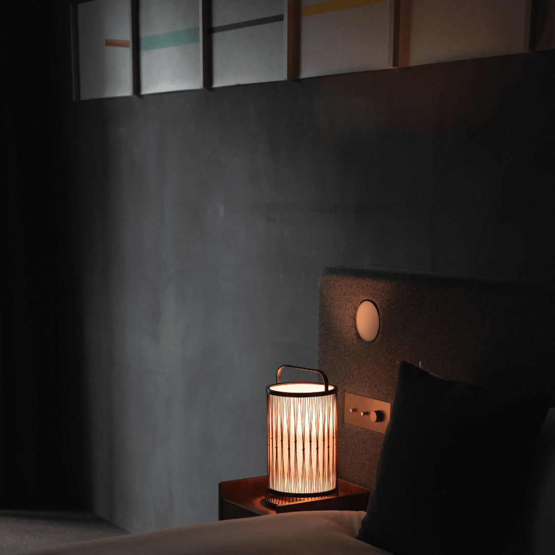 A Japanese bamboo lamp placed on a bedside table in a Japandi-style bedroom.