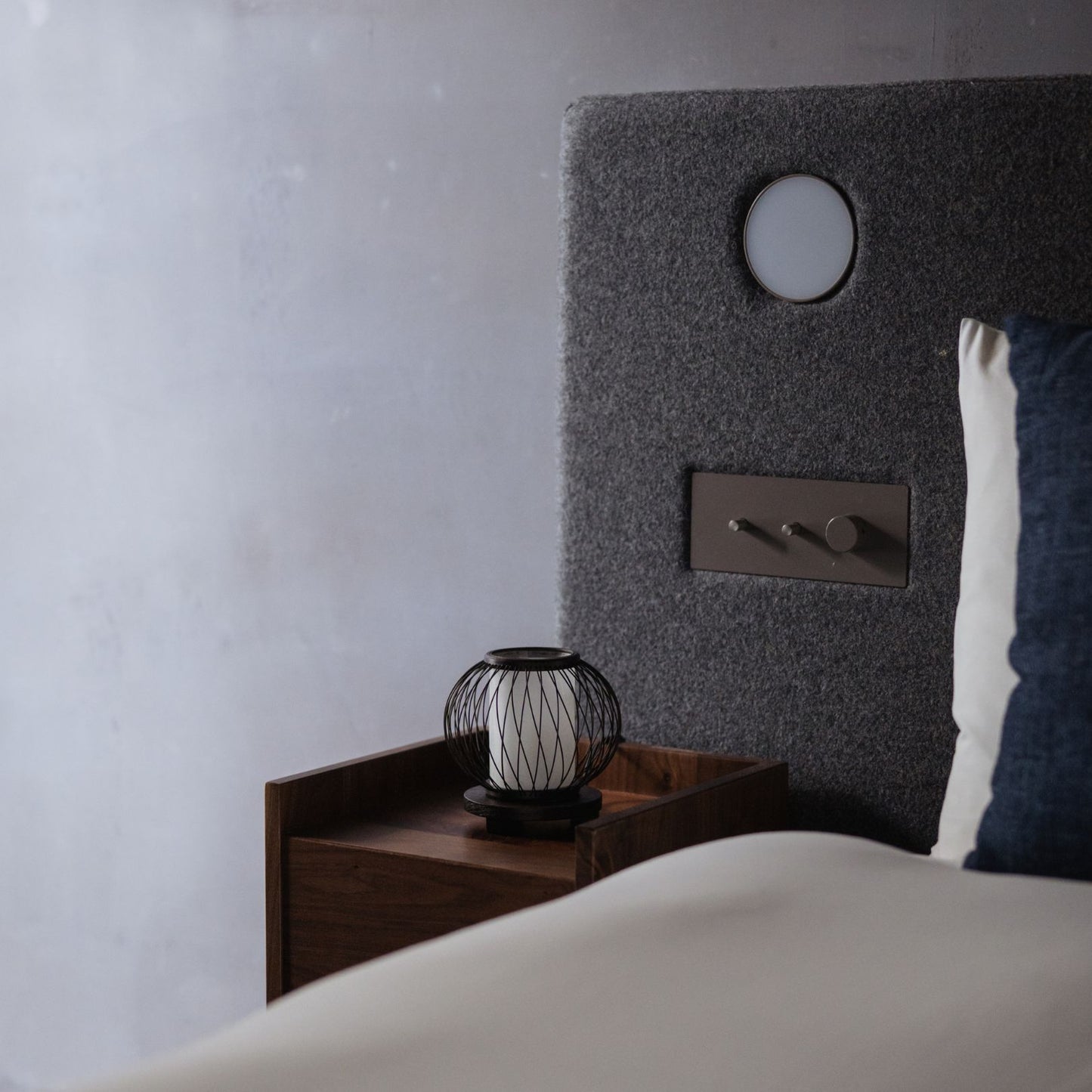 A Japanese bamboo table lamp placed on a bedside table in a Japandi-style bedroom.