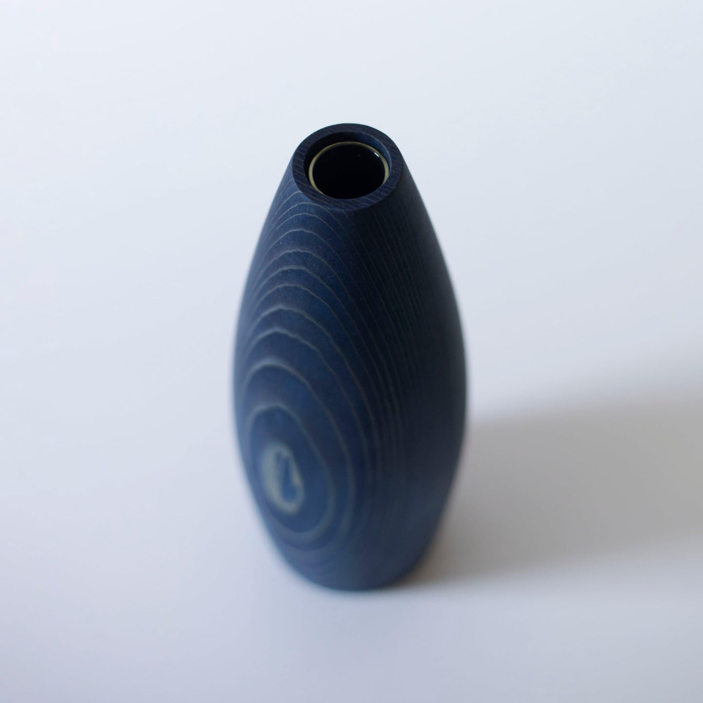 A minimalist, indigo-dyed cedar wood vase, showcasing the beauty of natural materials and Japanese craftsmanship.