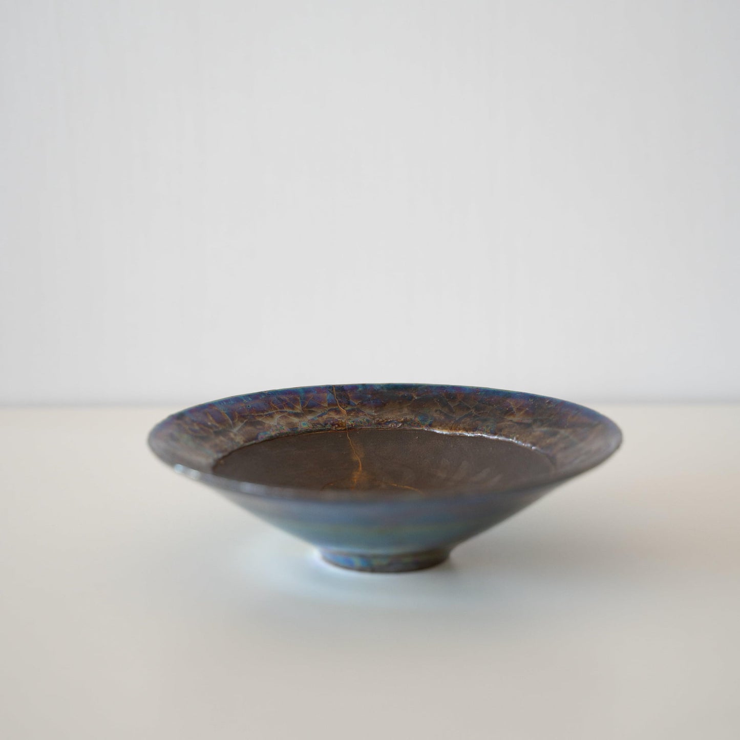 Japanese Kintsugi bowl in deep brown with a gold repair, showcasing the beauty of imperfection.