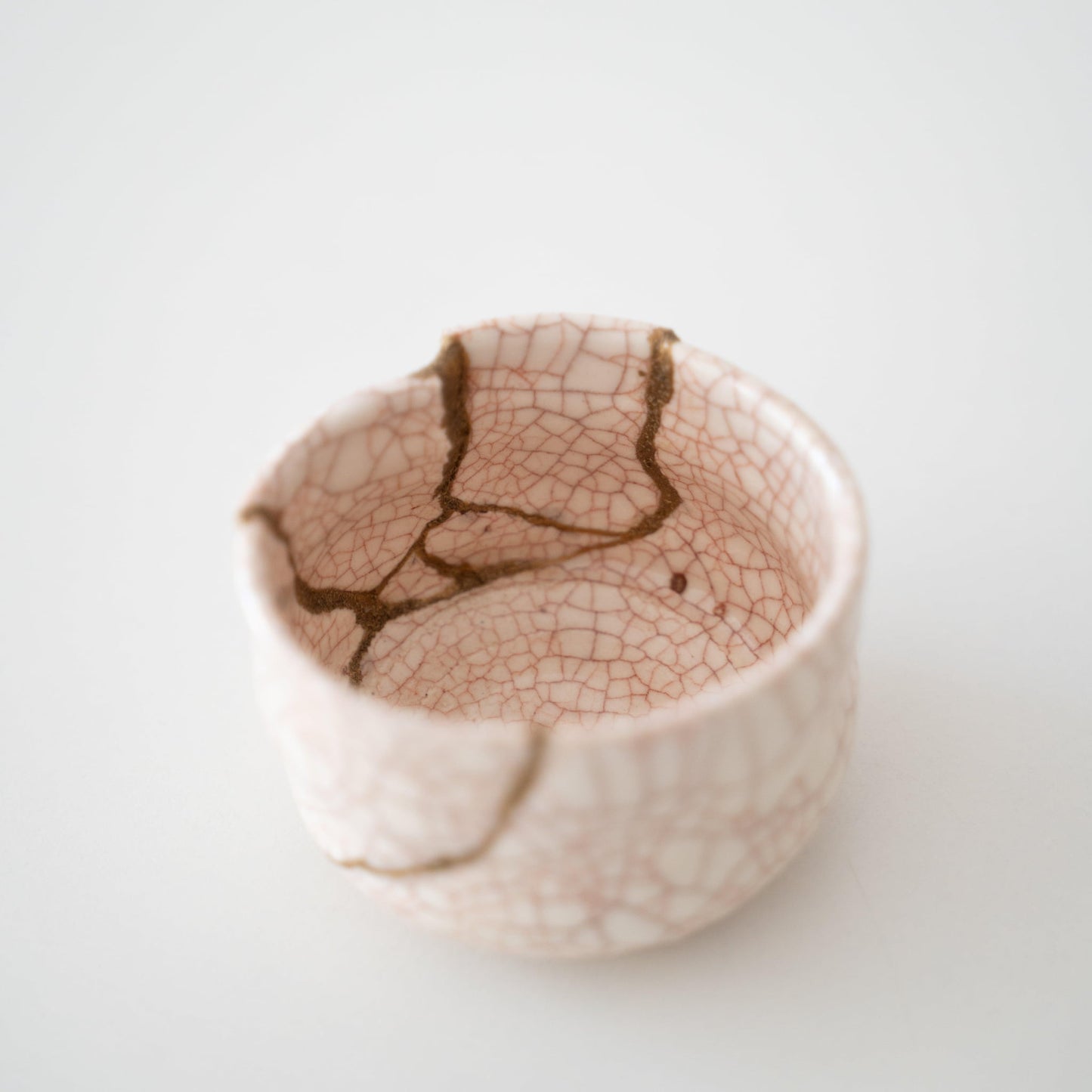 White tea bowl repaired with Kintsugi, a traditional Japanese technique, presented in a paulownia wood box.