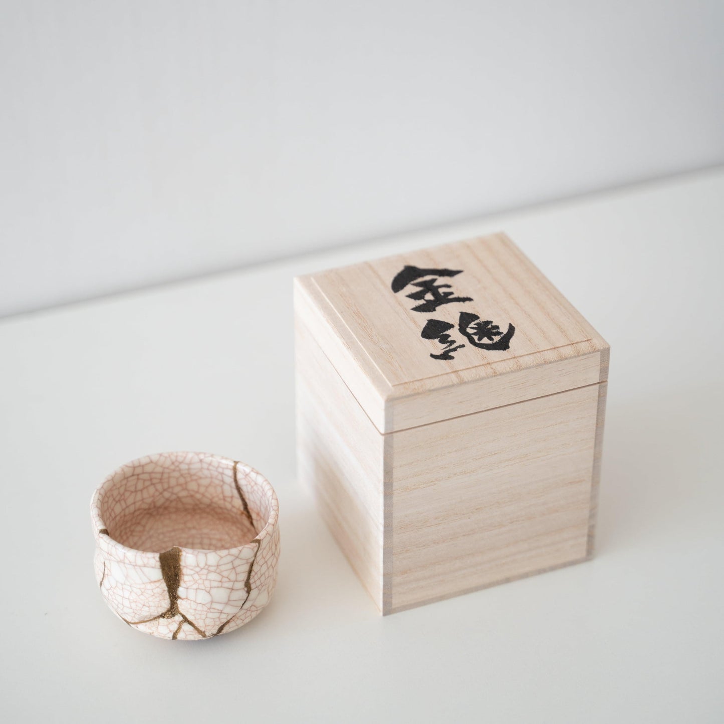 Gift set of a white tea bowl repaired with Kintsugi, a traditional Japanese technique, and a paulownia wood box.