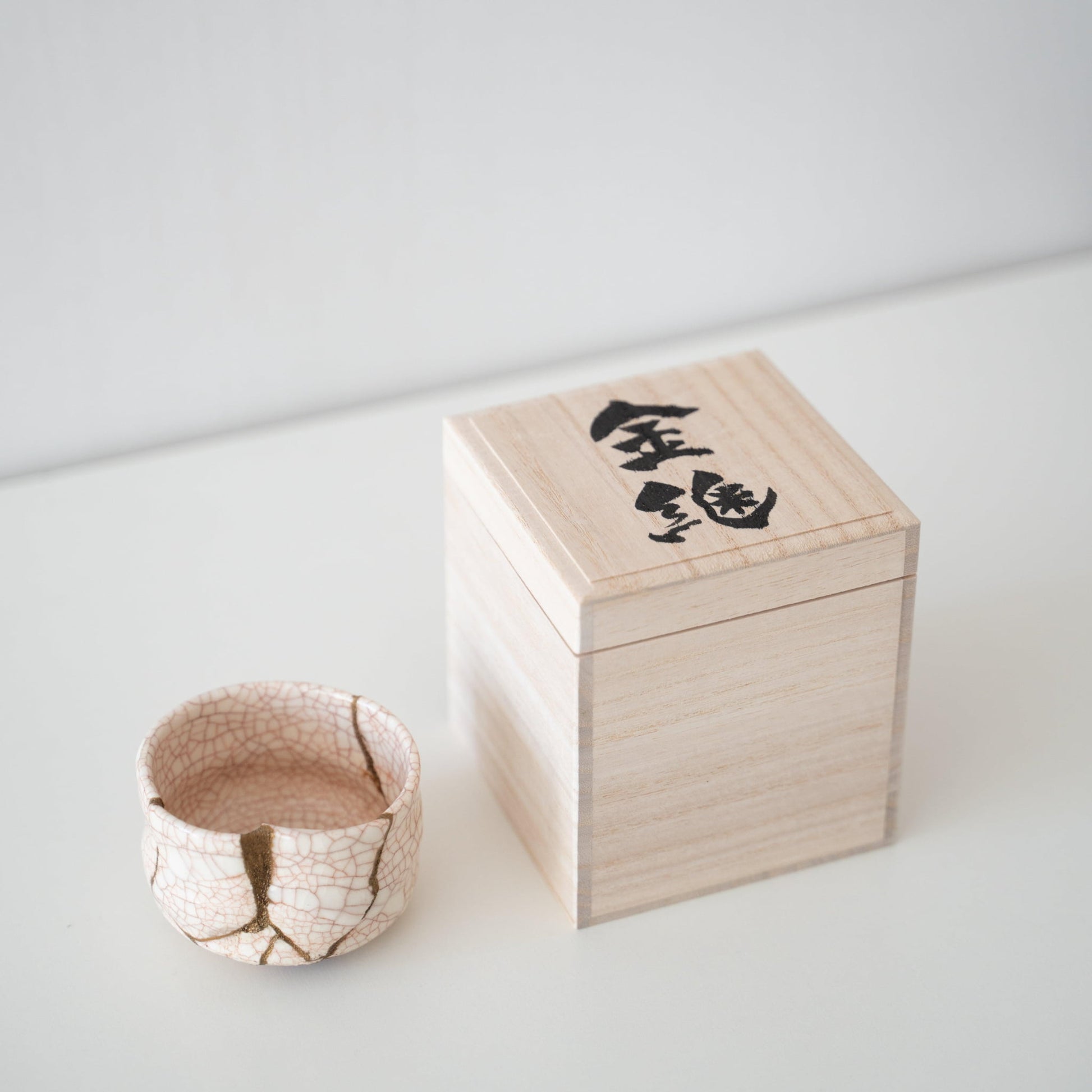 Gift set of a white tea bowl repaired with Kintsugi, a traditional Japanese technique, and a paulownia wood box.