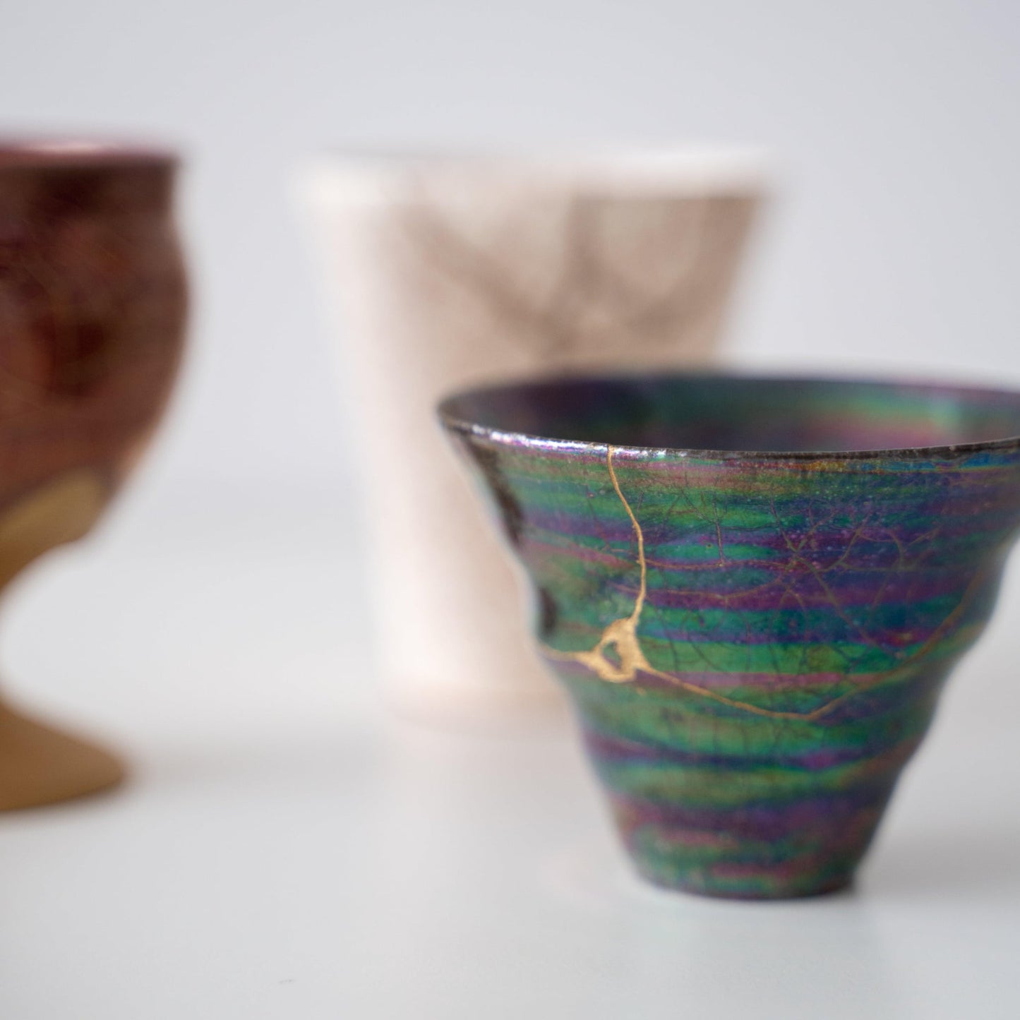 Close-up of an iridescent coral-shaped cup repaired with Kintsugi, a traditional Japanese technique, showcasing the beautiful golden joinery.