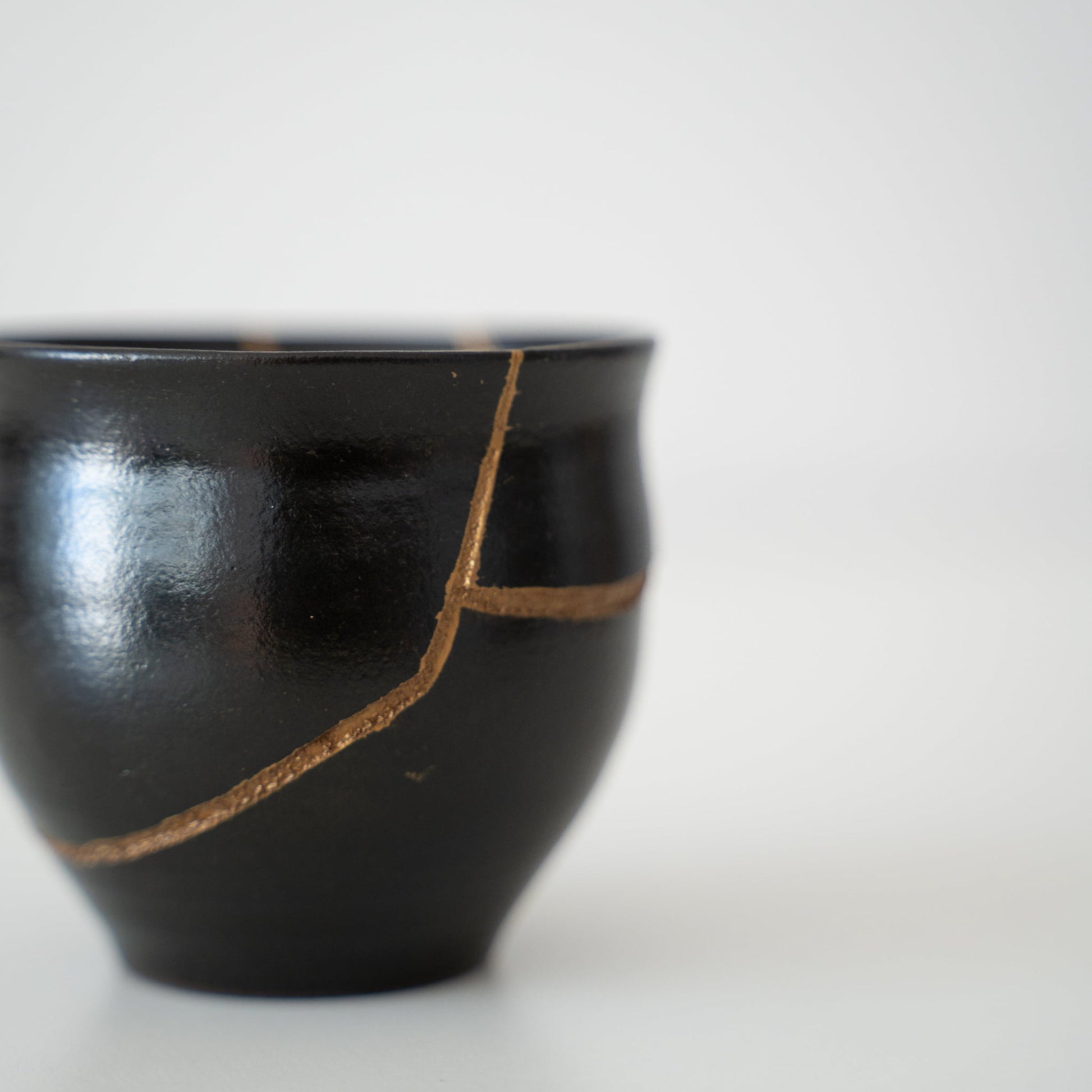 Japanese sake cup repaired with Kintsugi, a traditional Japanese technique, featuring black lacquer