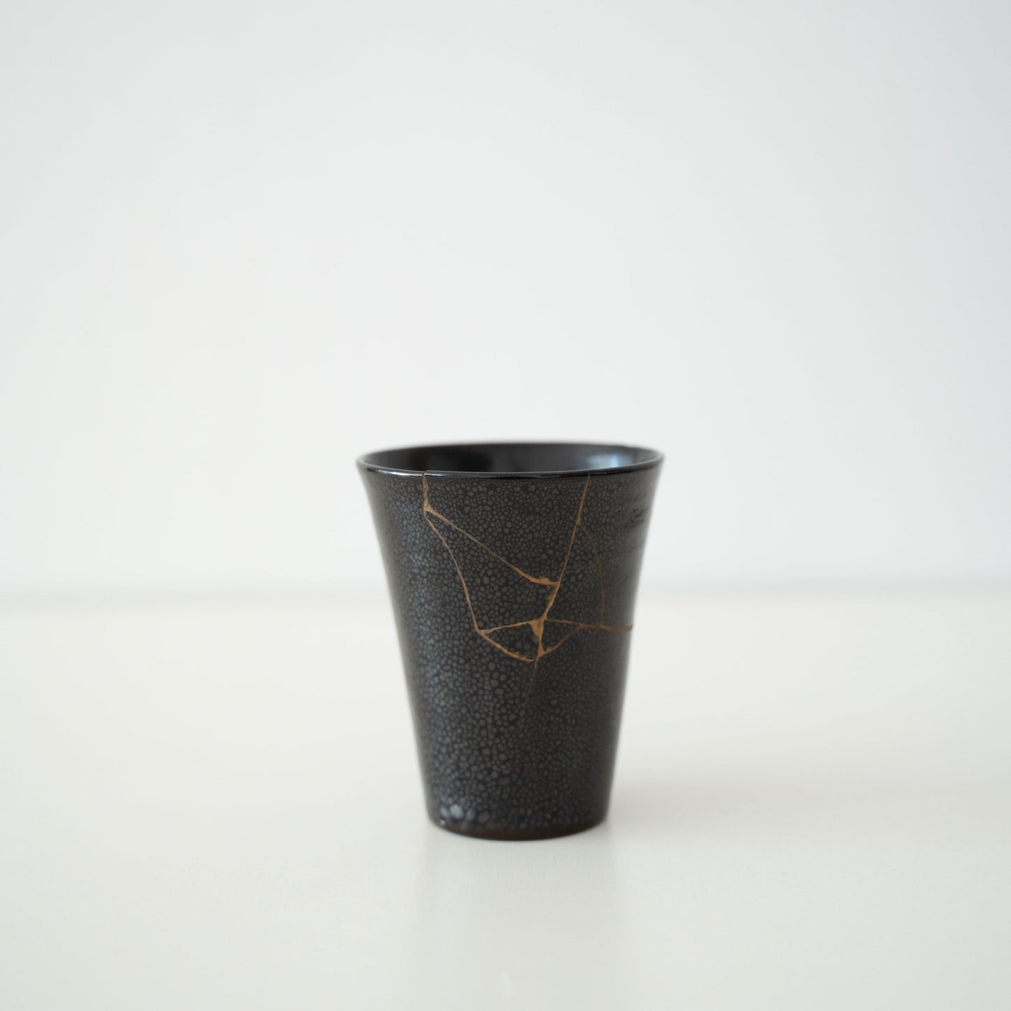 Japanese cup repaired with Kintsugi, a traditional Japanese technique, featuring black lacquer and named "Shikkoku Rai" (Jet-Black Thunder).