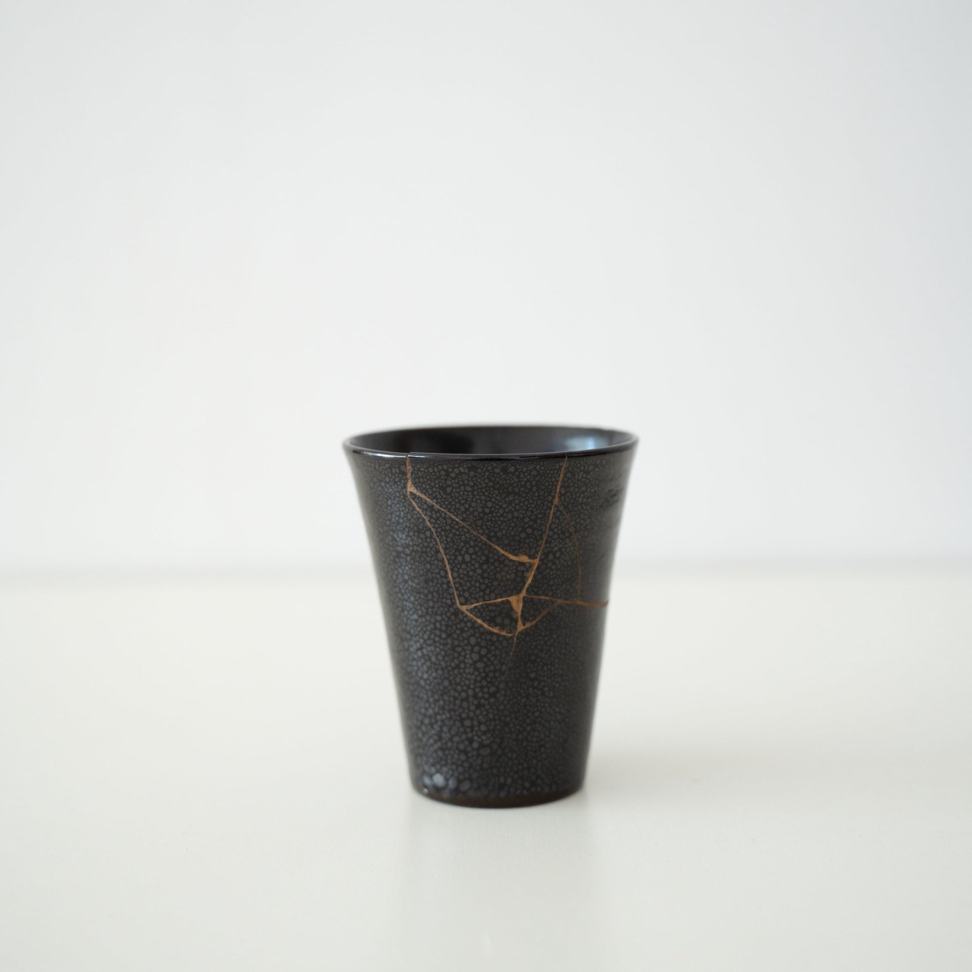 Japanese cup repaired with Kintsugi, a traditional Japanese technique, featuring black lacquer and named "Shikkoku Rai" (Jet-Black Thunder).