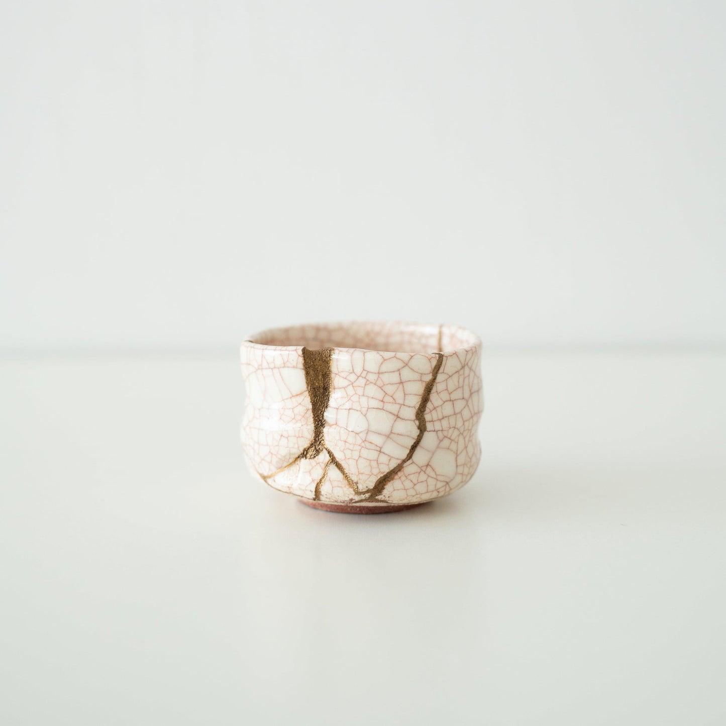 White tea bowl repaired with Kintsugi, a traditional Japanese technique, showcasing the golden joinery.