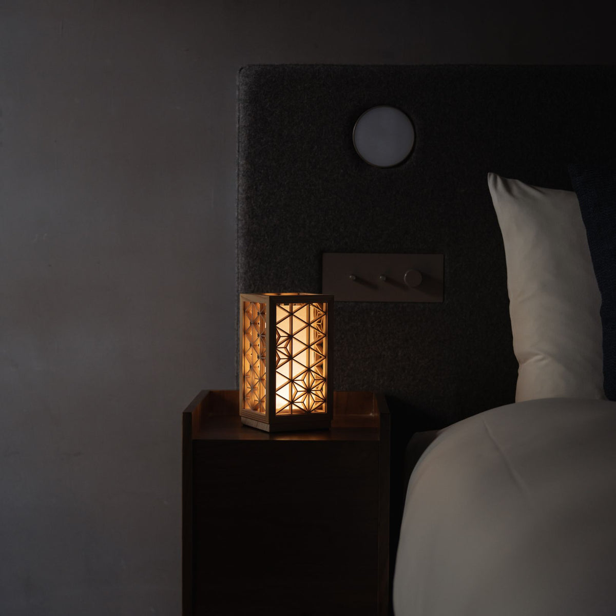 Lampe de table japonaise Kumiko "Asanoha" extra petite allumée sur une table de chevet en bois