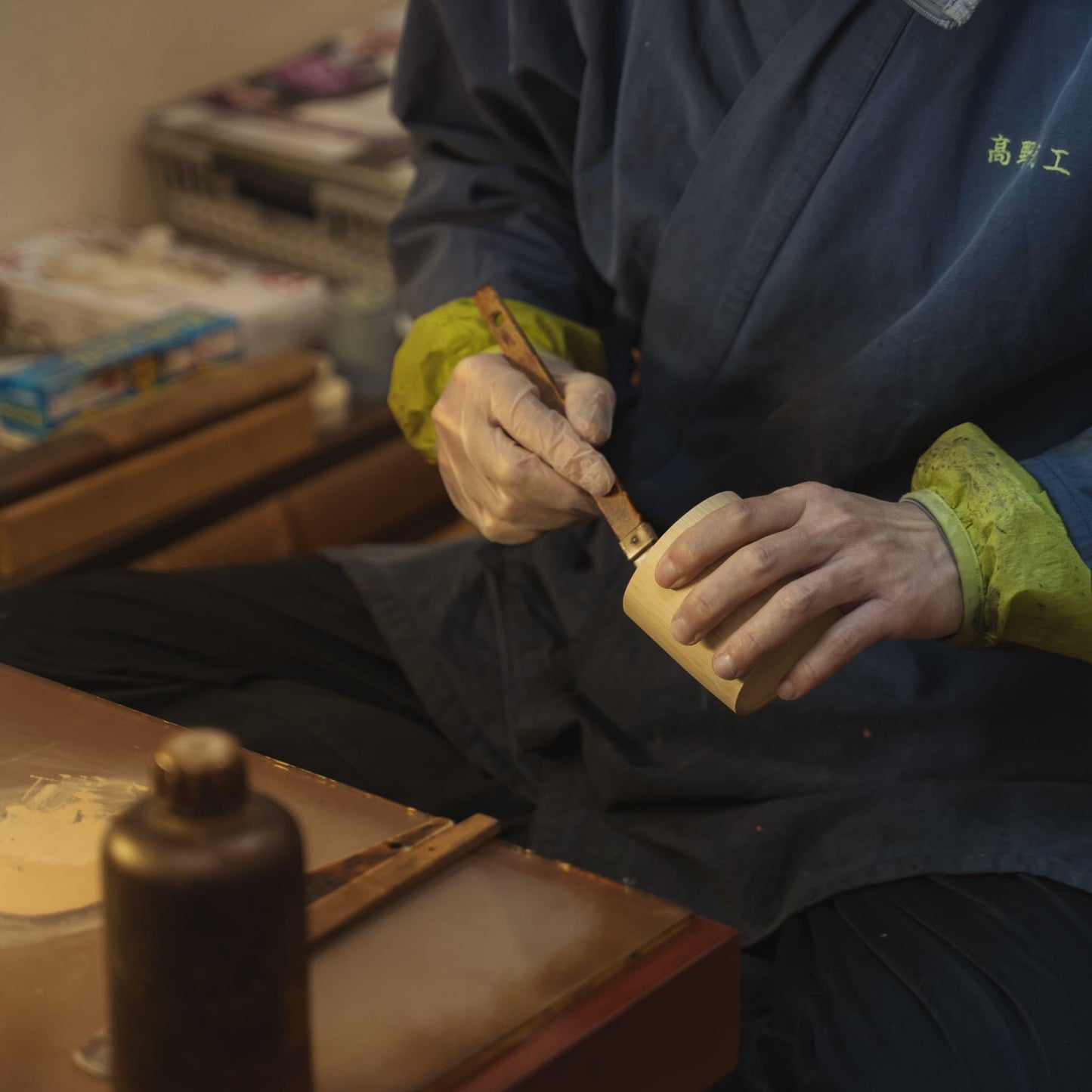 Japanese artisan applying lacquer to a bamboo cup, showcasing traditional craftsmanship.