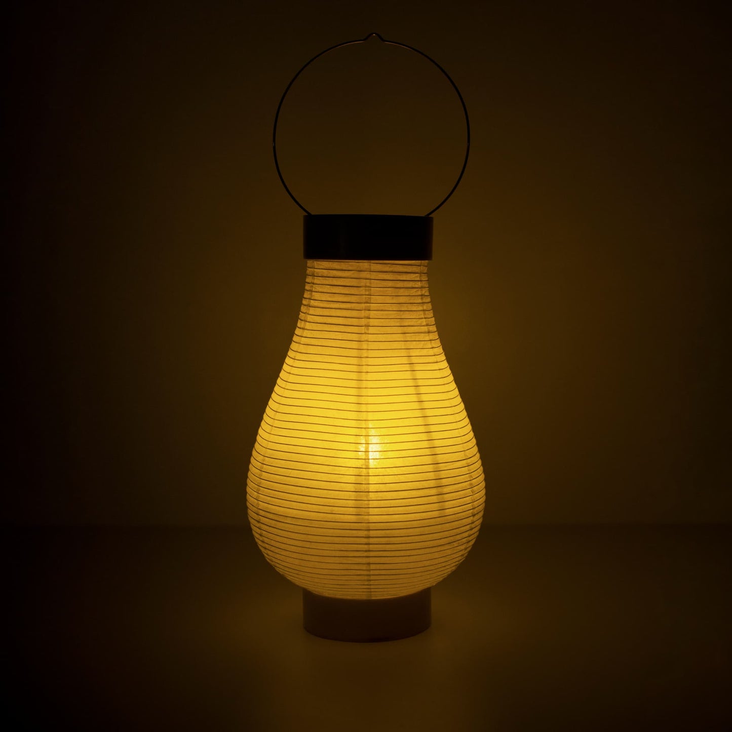 A traditional Japanese paper lantern lamp emitting warm light in a dark room