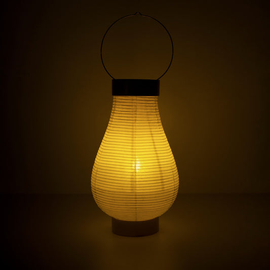 A traditional Japanese paper lantern lamp emitting warm light in a dark room