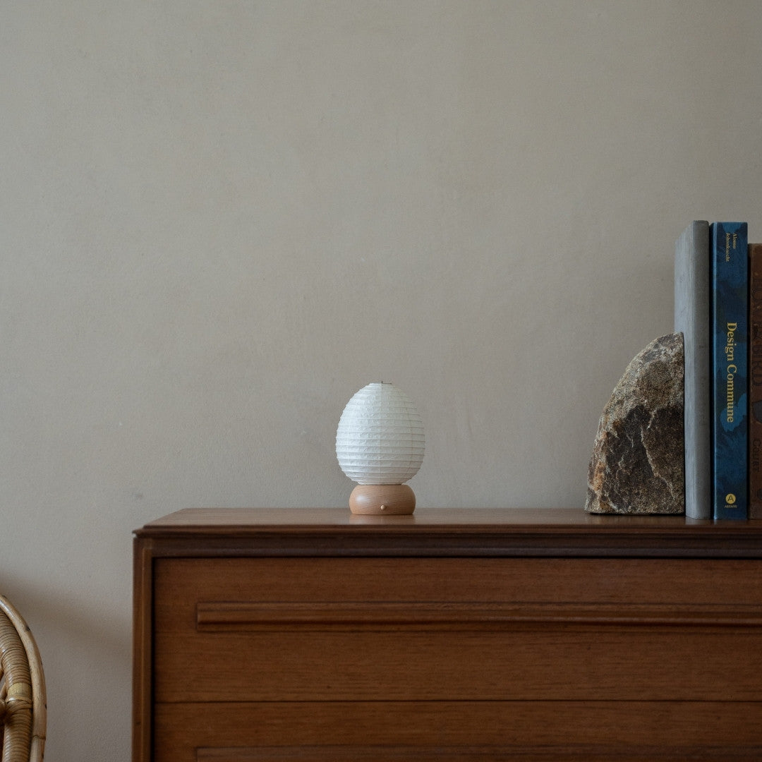 Japanese Paper Table Lamp "Mini Egg" on wooden shelf in Japandi style living room – Unique portable paper lamp for Japandi living room