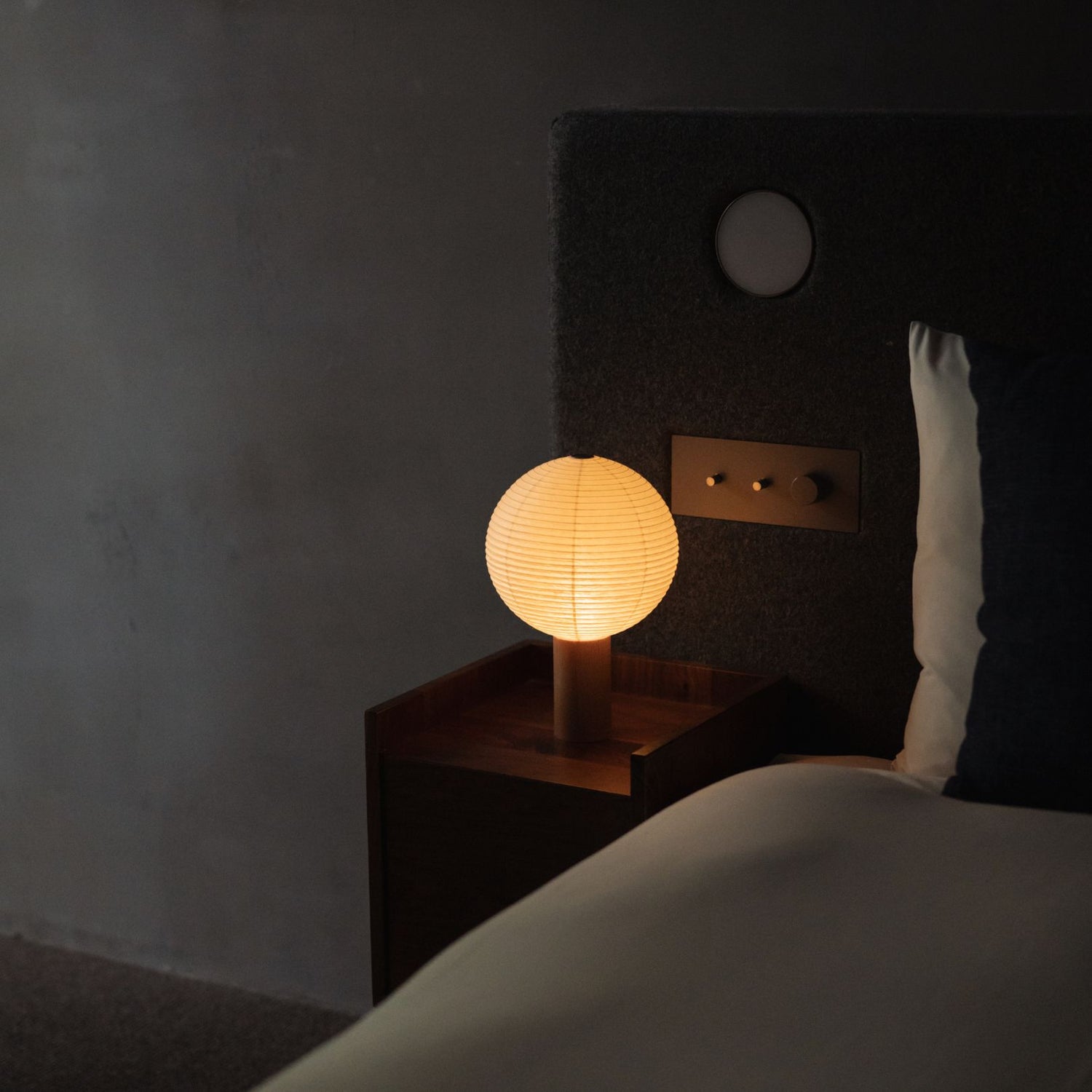 A Japanese paper touch lamp "TORCHIN CIRCLE" on a bedside table.