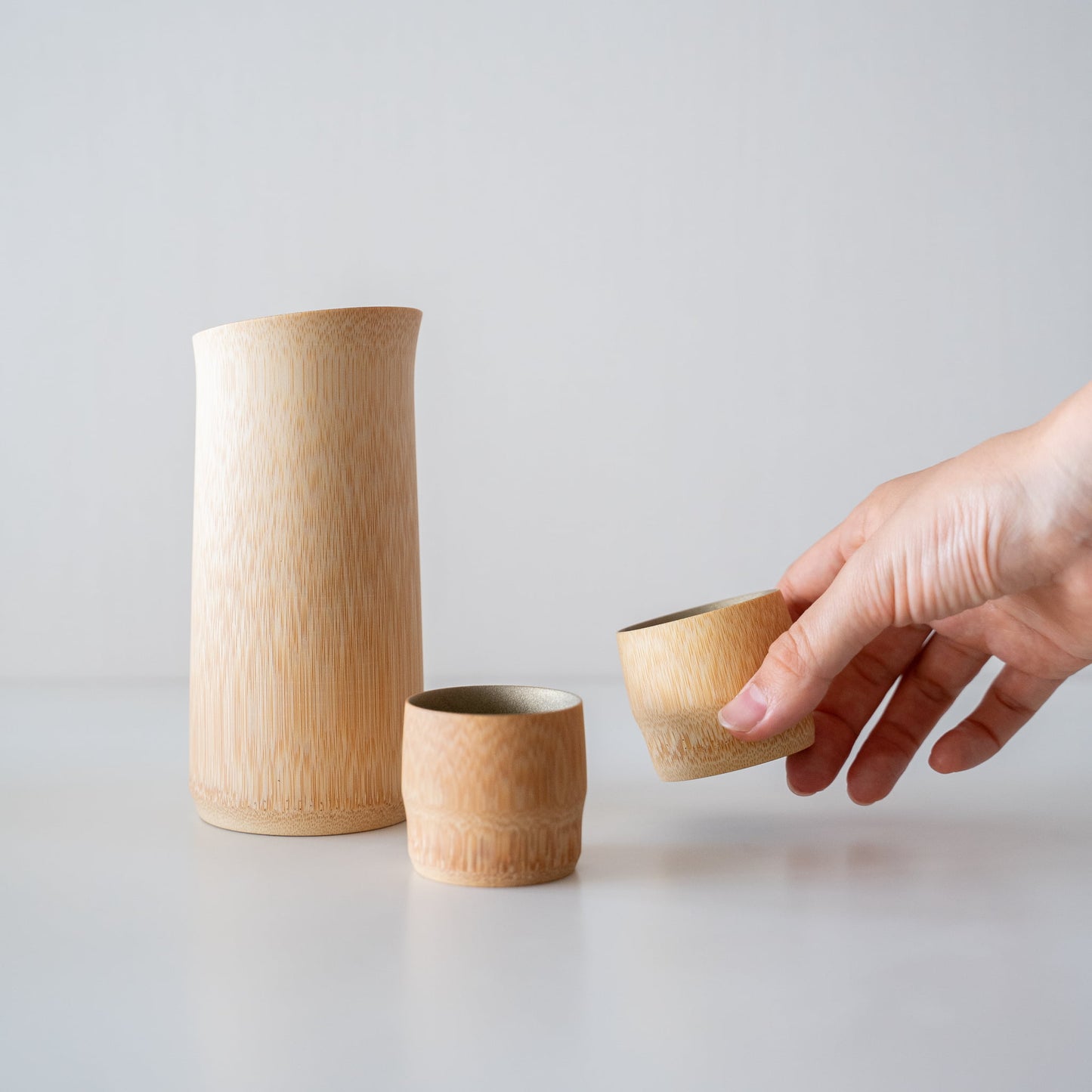 Hand holding a bamboo sake cup, crafted with traditional techniques from Kyoto, Japan.