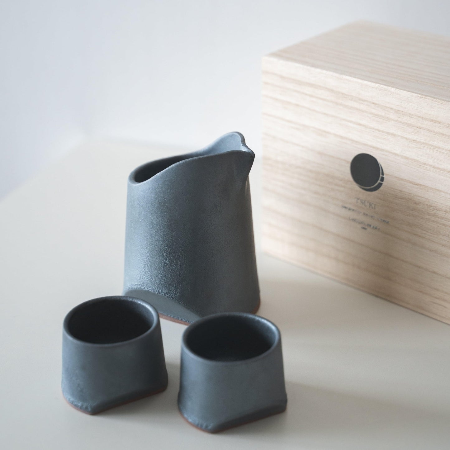 Gift set of iron-colored sake pitcher and two cups, crafted using traditional Japanese roof tile techniques, presented in a paulownia wood box.