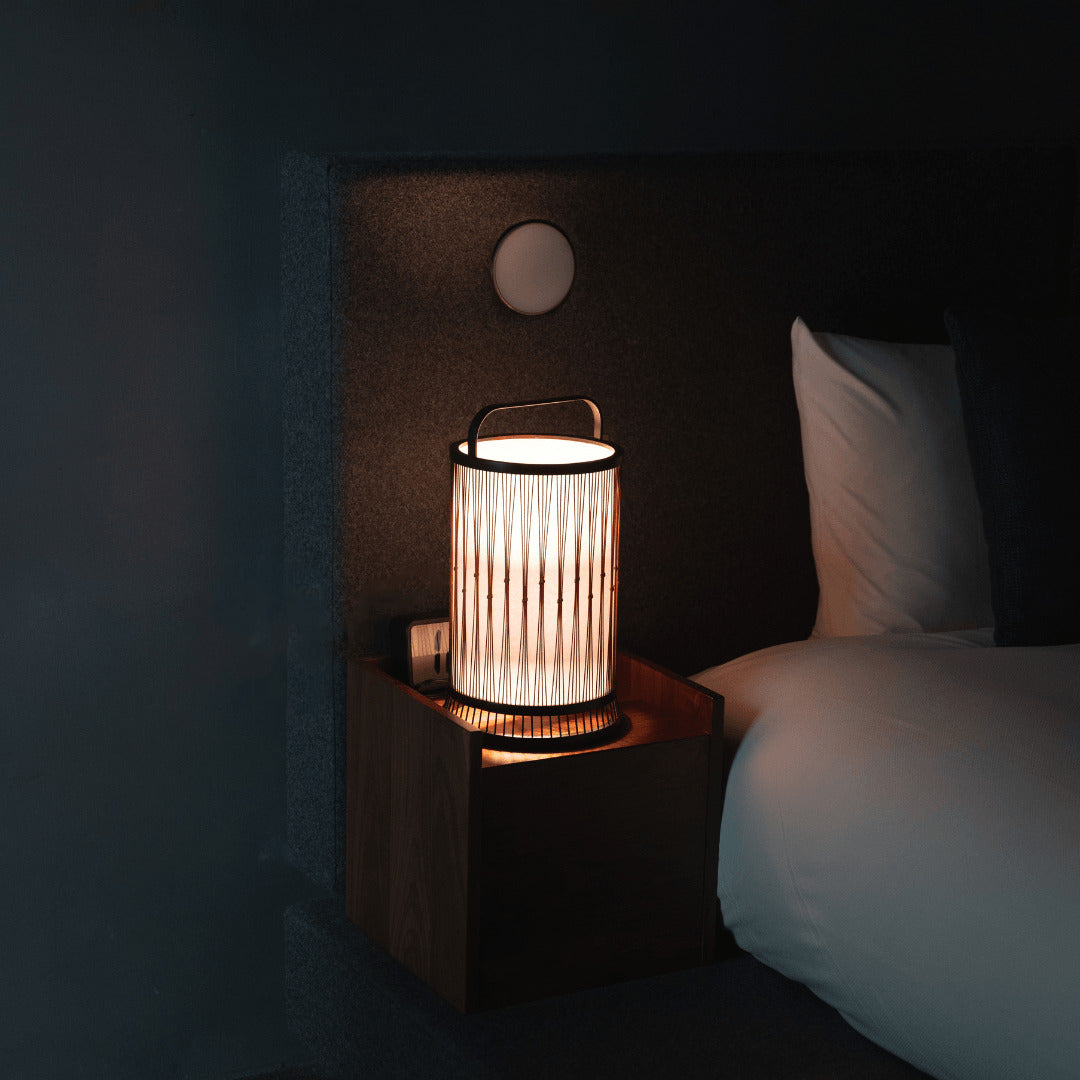 Traditional Japanese bamboo lamp, crafted with 800-year-old Shizuoka techniques, resting on a bedside table.