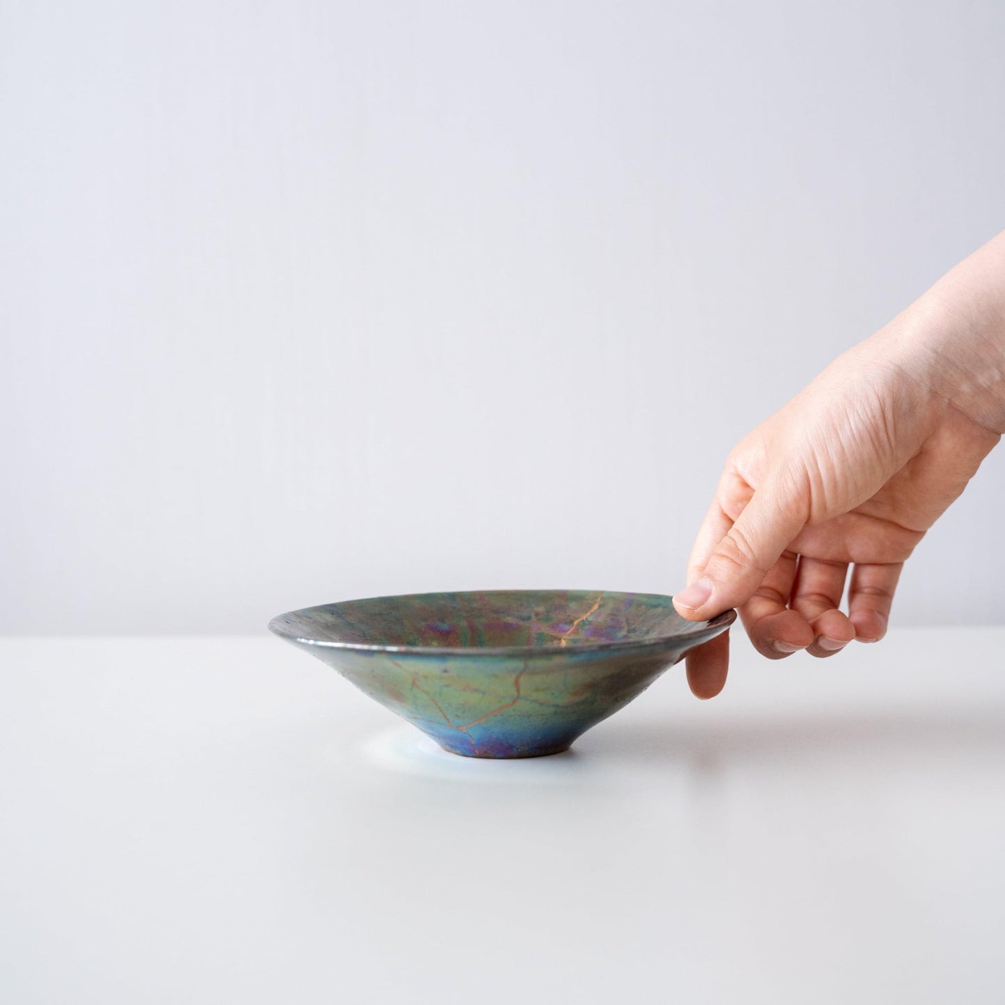 Hand holding Kintsugi Bowl "Green Nebula", showing its size and how it fits in the hand