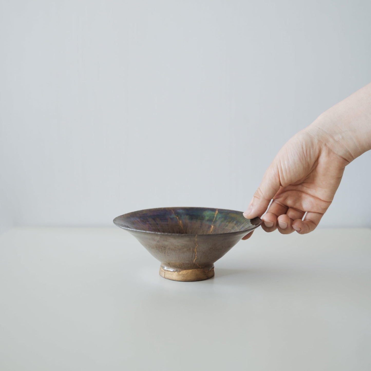 Hand holding Kintsugi Bowl "Iris Rose", showing its size and how it fits in the hand