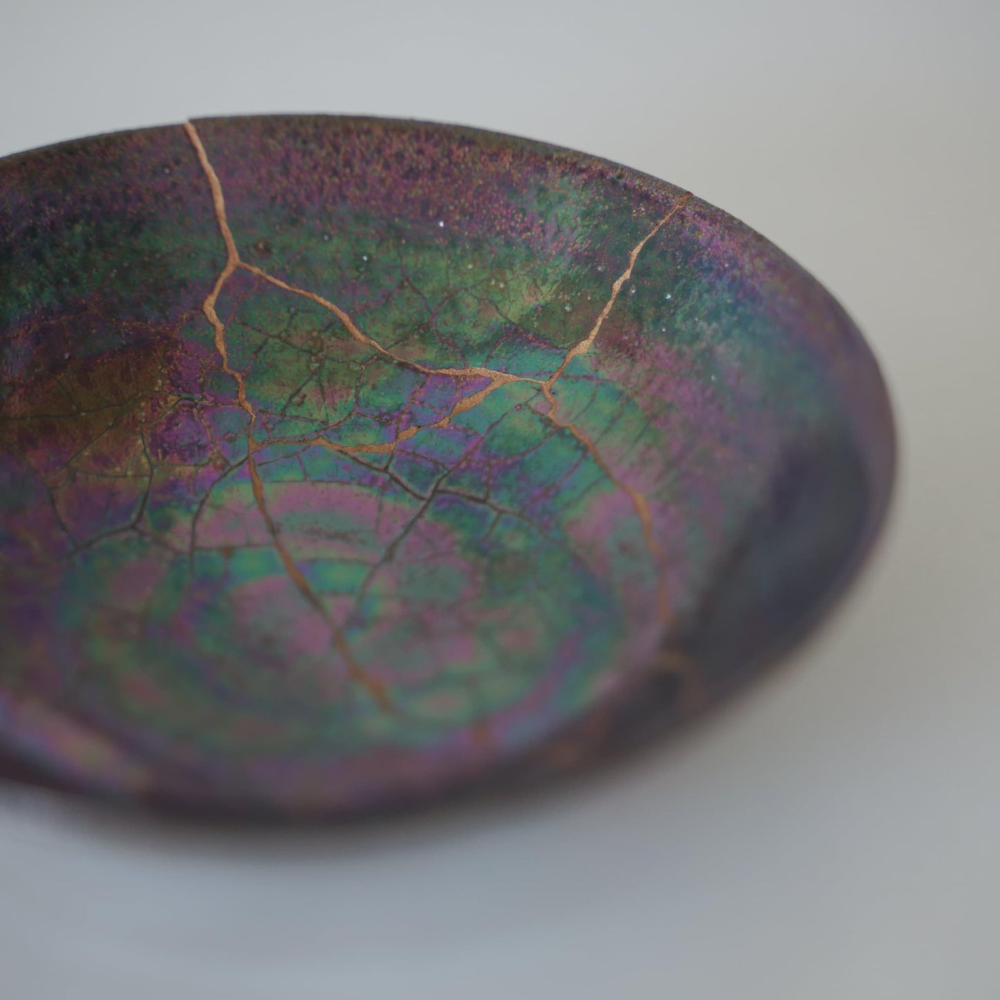 Iridescent bowl repaired with kintsugi, the traditional Japanese art of mending broken pottery with gold lacquer.