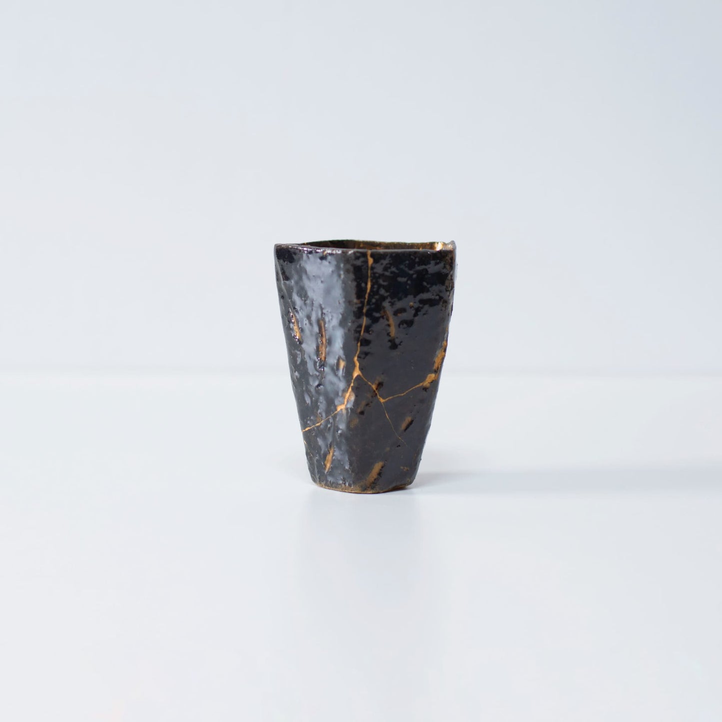 Side view of Pentagon Kintsugi Cup "Tenmoku" Black 02 against white background