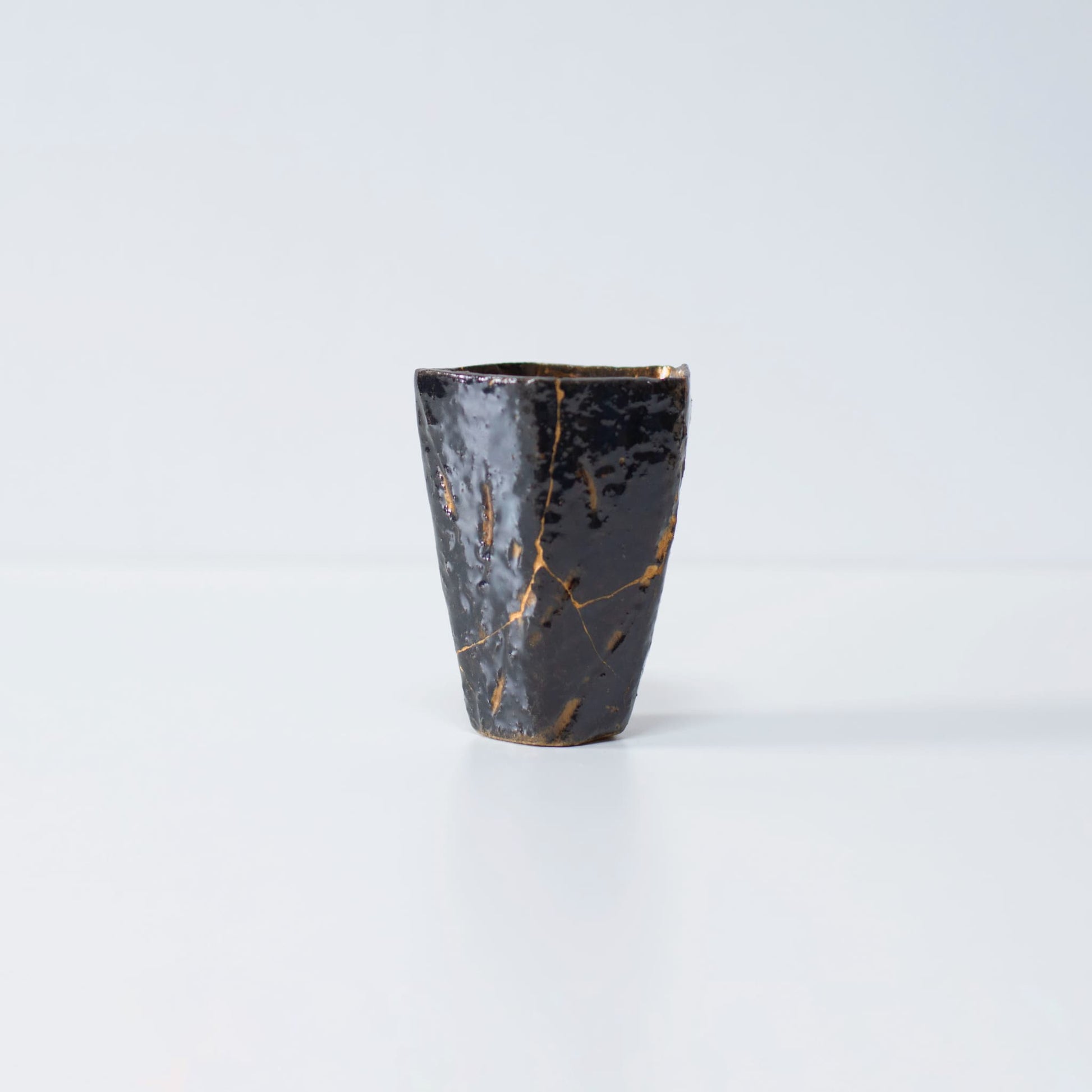Side view of Pentagon Kintsugi Cup "Tenmoku" Black 02 against white background