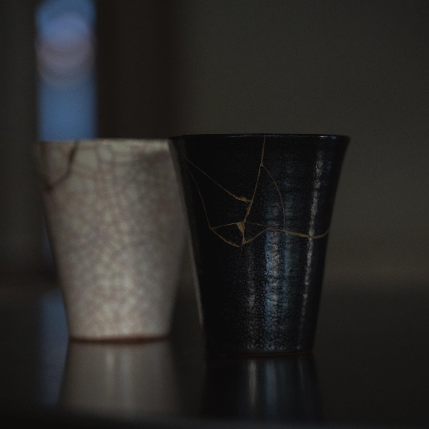 Kintsugi Cup "Jet Black Lightning" with "Vermilion Crackle" 01 in Background: Side View on Black Table