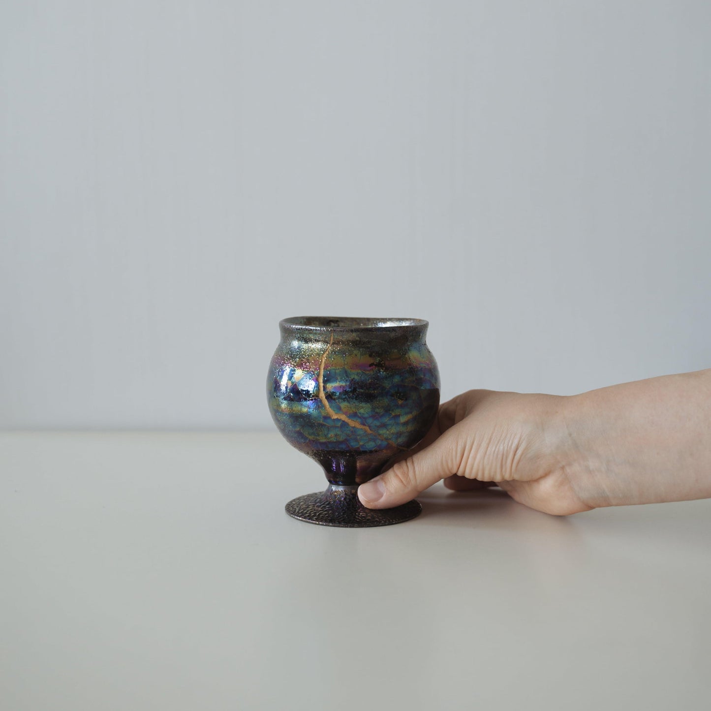 Hand holding Kintsugi Goblet "The Dawn Starry Sky", showing its size and how it fits in the hand