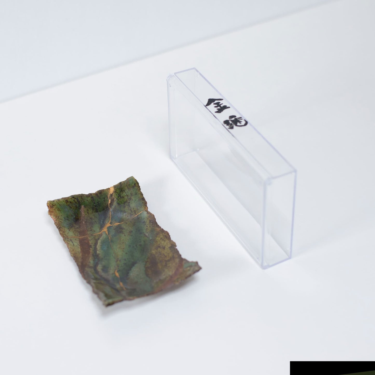 Kintsugi Plate "Oribe" Deep Green 01 presented in a clear case, top view.